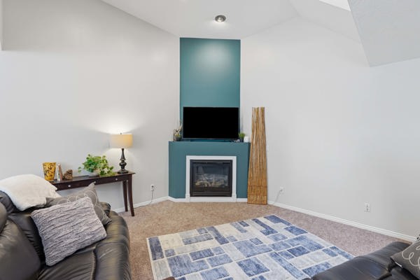 Living space featuring a fireplace with a painted mantel, vaulted ceilings, and recessed lighting