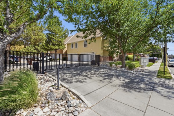 Gated driveway entrance featuring black iron fencing and an automatic gate system