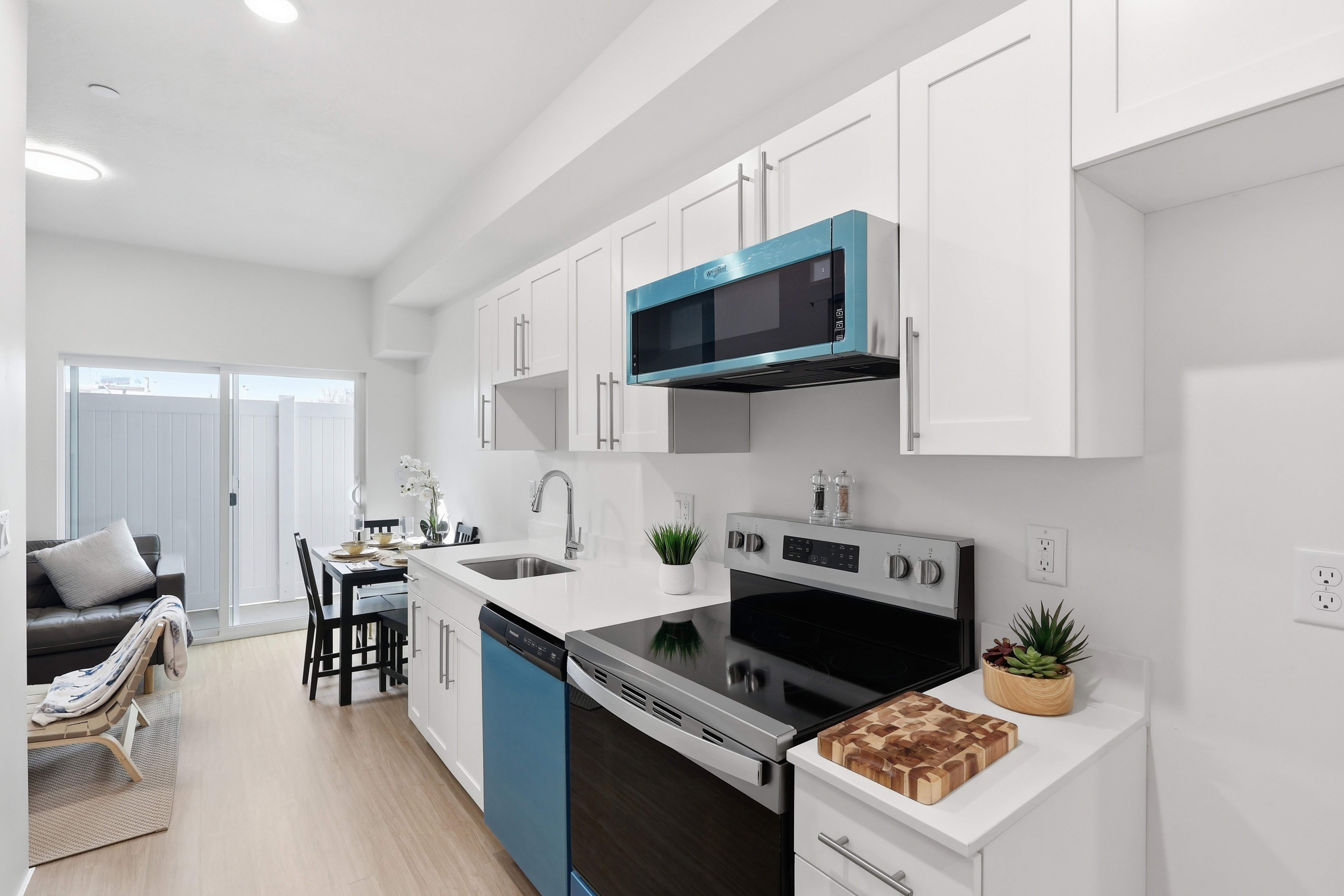 Kitchen featuring white cabinetry with silver-tone hardware, a light-toned countertop, a stainless steel range, a contrasting blue dishwasher, and an over-the-range microwave