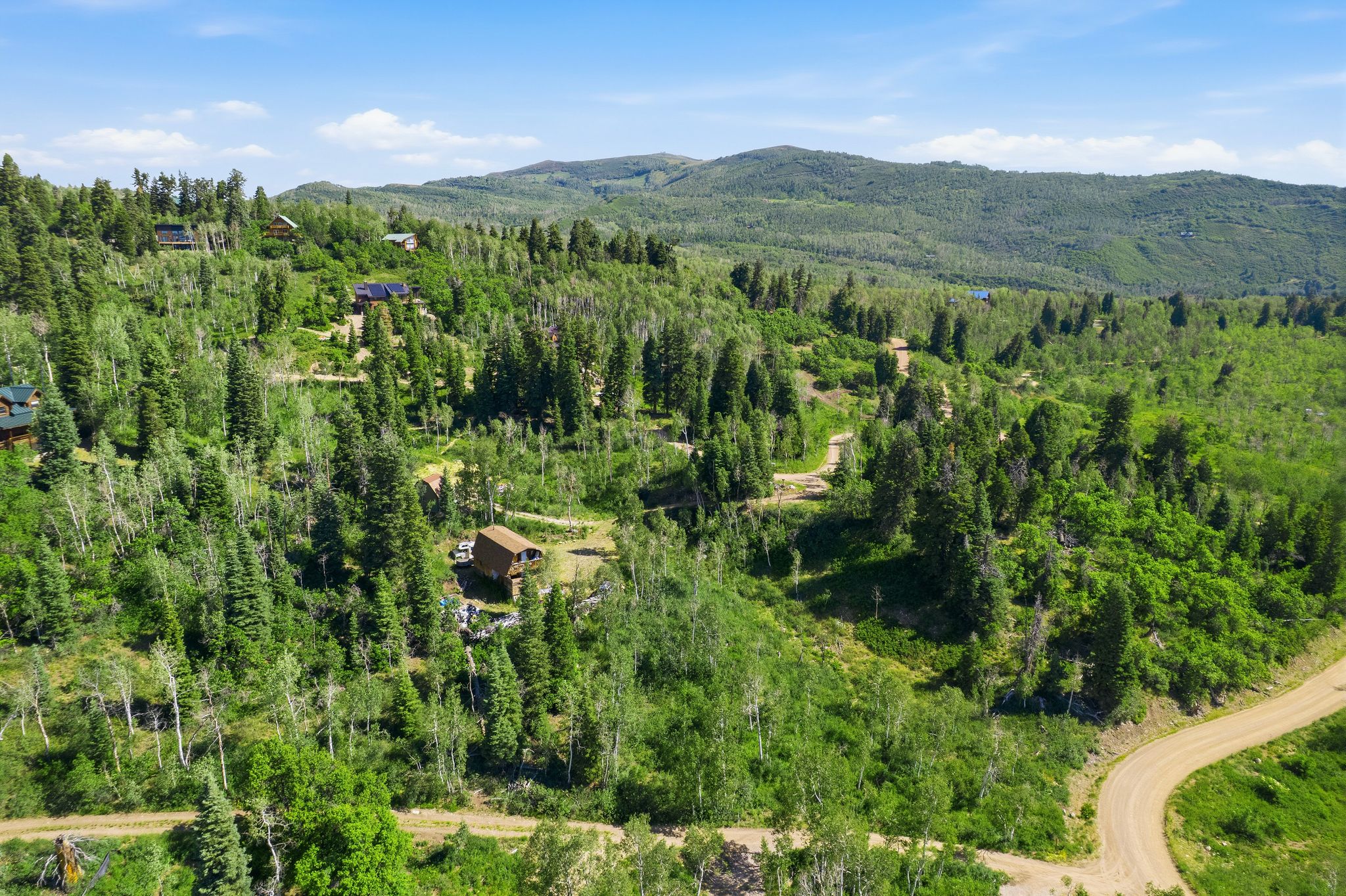 Expansive mountain landscape featuring dense forestation and multiple residential structures
