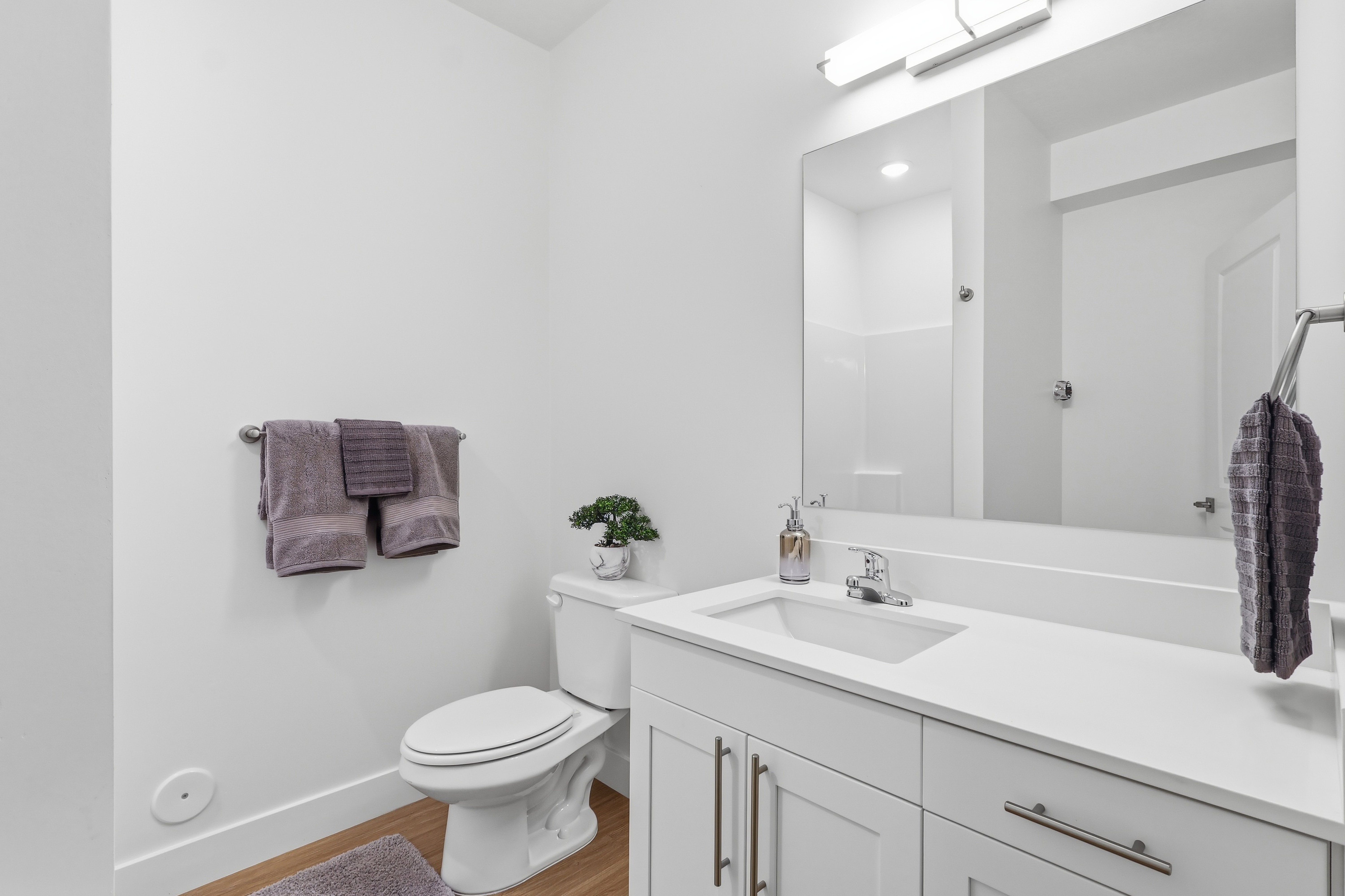 Bathroom featuring a white vanity with an integrated sink, polished chrome faucet, and expansive wall-mounted mirror