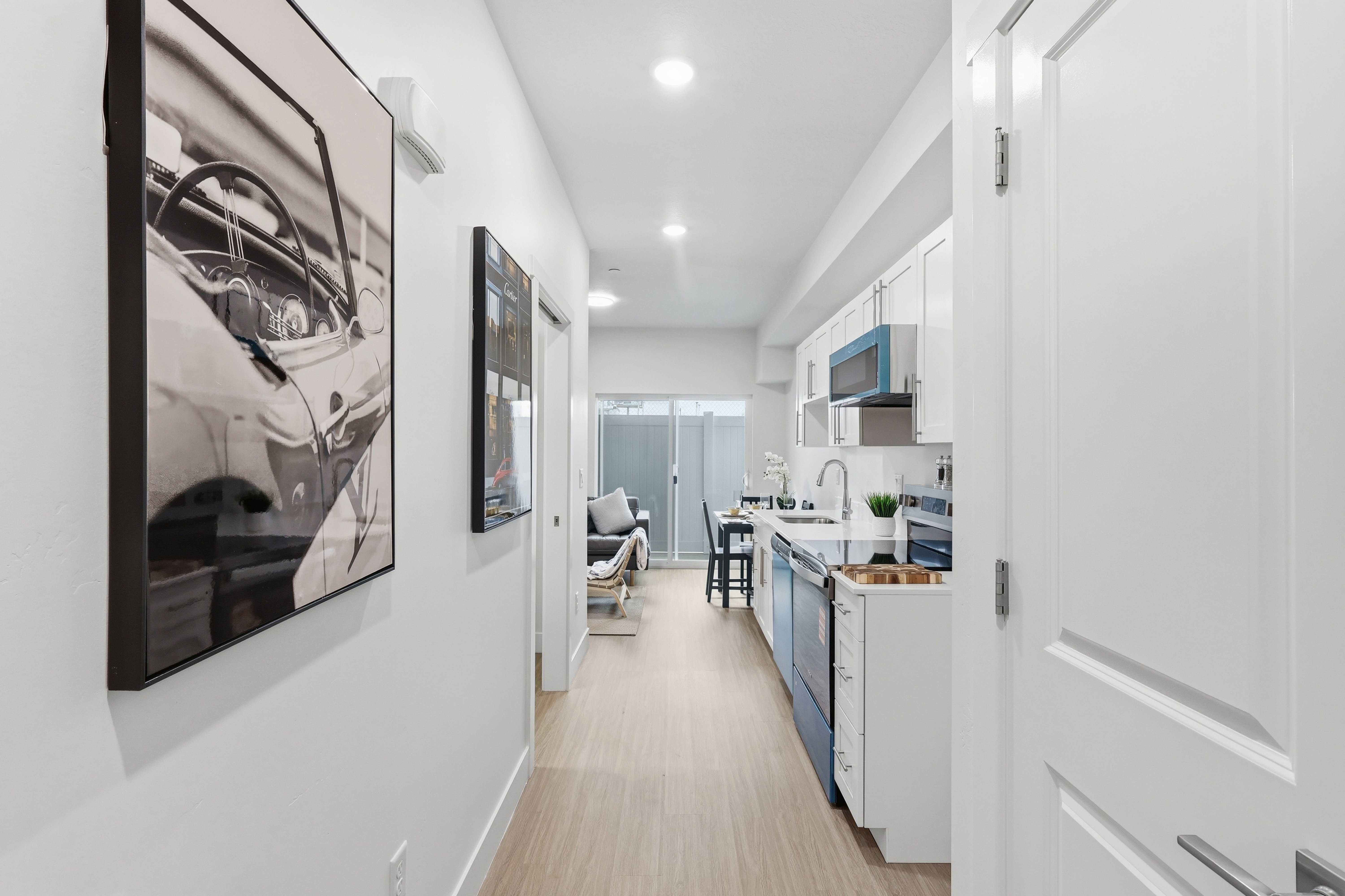 Contemporary kitchen featuring white cabinetry, light-colored wood-finish flooring, recessed lighting, stainless steel appliances, and a white countertop