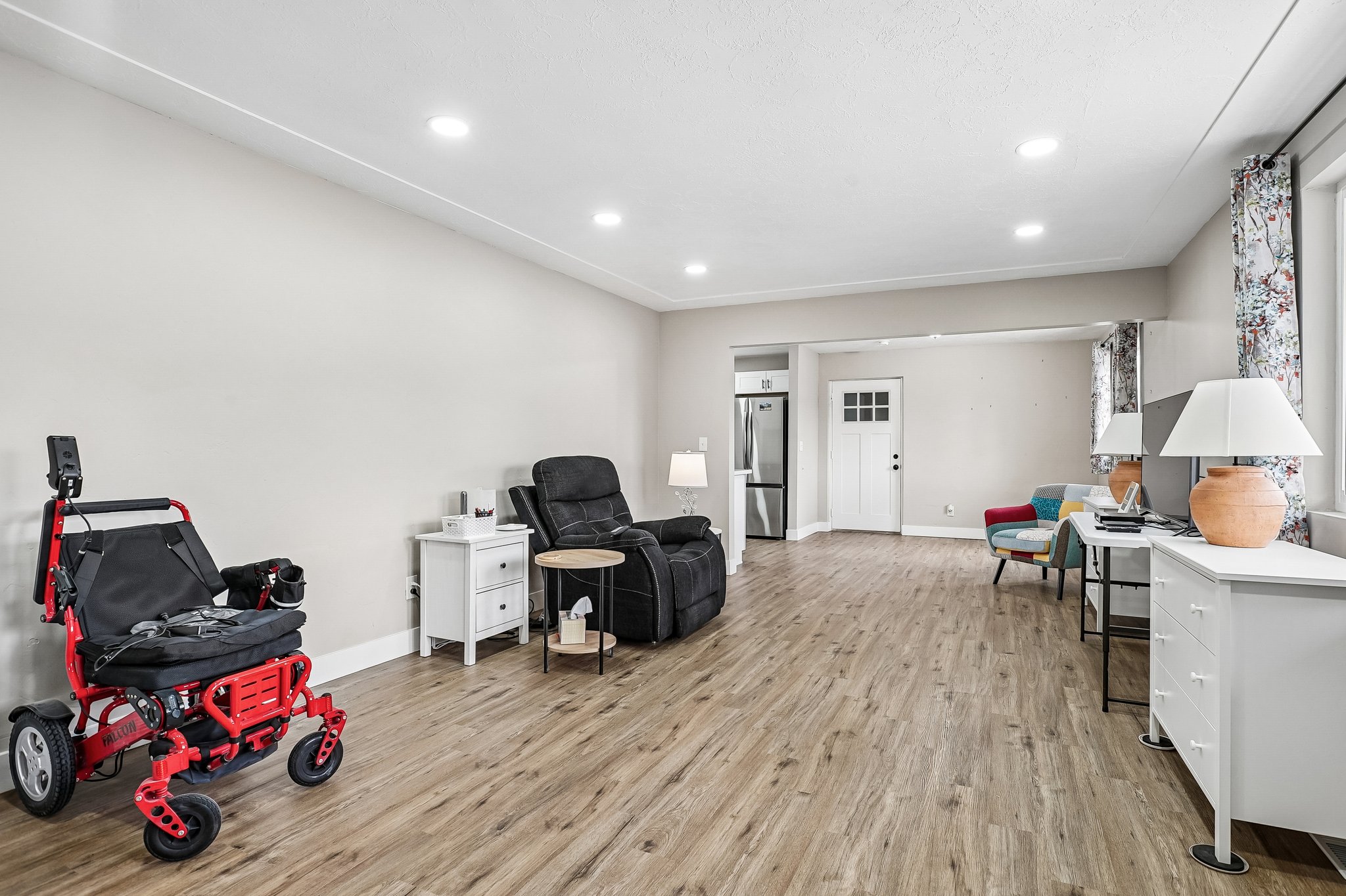 Spacious interior with wood-finish flooring, recessed lighting, crown molding, and a white paneled door with windowpanes
