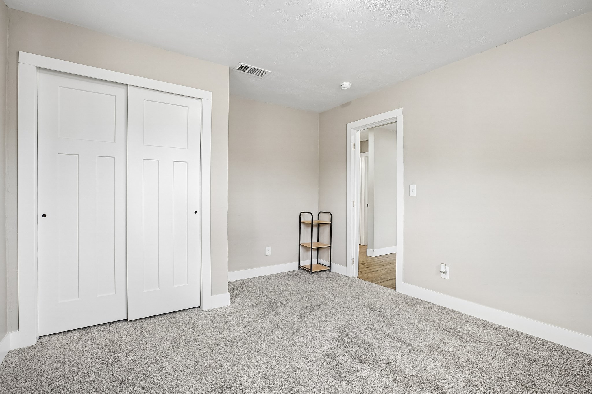 Bedroom featuring light gray walls, gray carpeting, white trim, and a white sliding closet door