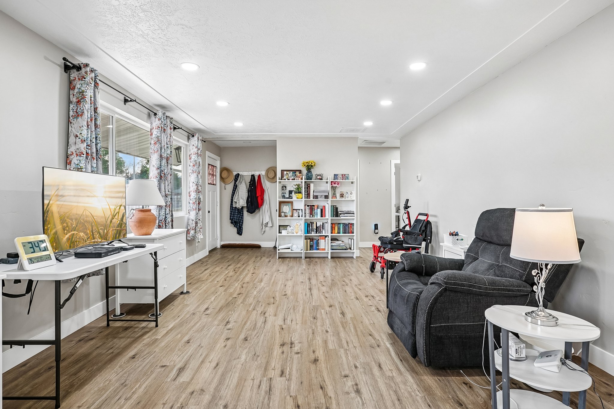 Spacious living area featuring wood-finish flooring, recessed lighting, and ample natural light from multiple windows