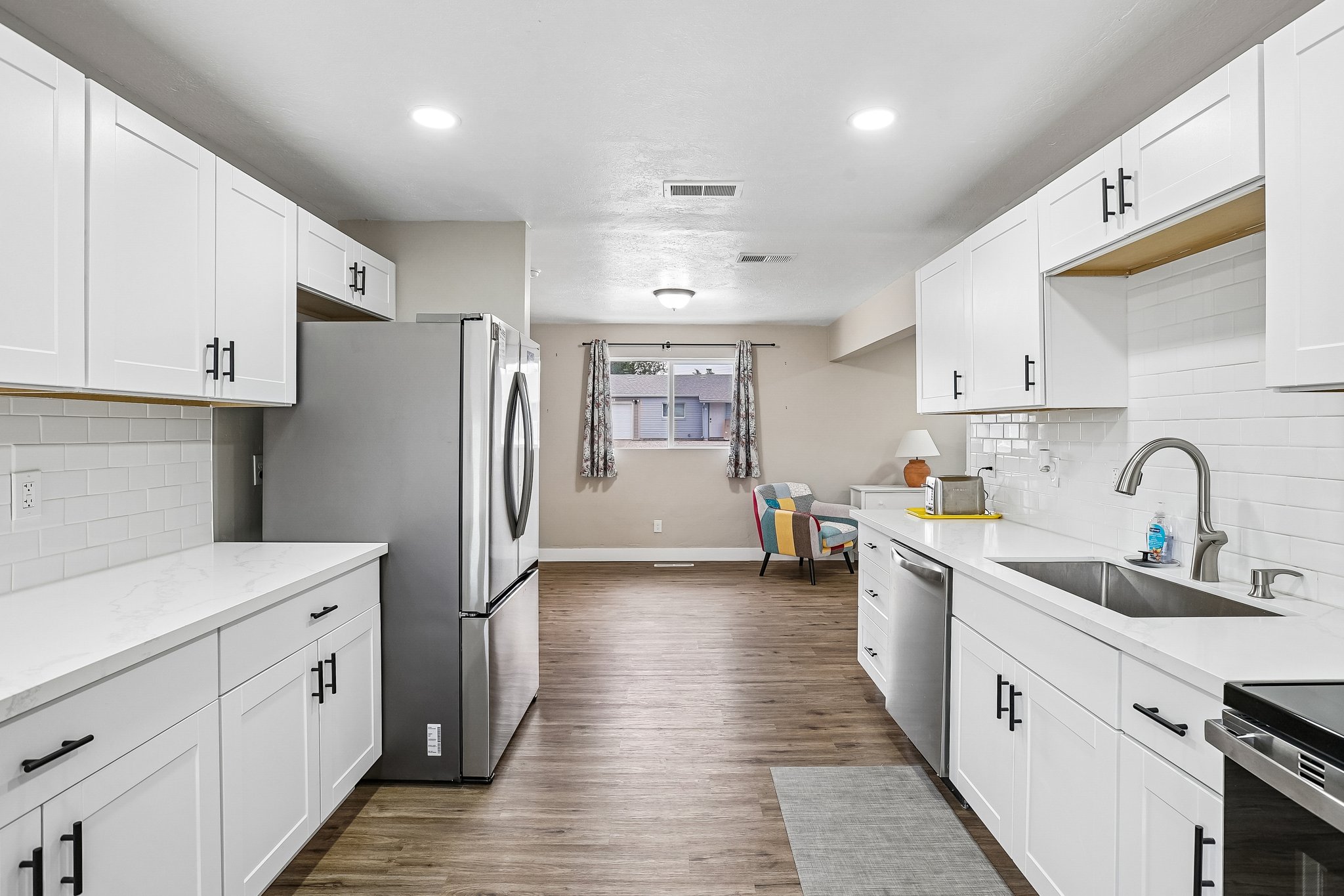 Modern kitchen featuring white shaker cabinetry with black hardware, white countertops, and a white subway tile backsplash