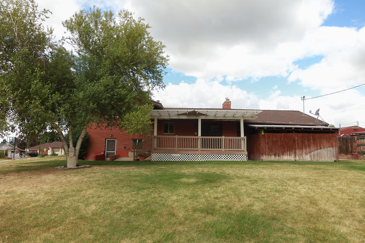 Spacious backyard with mature tree, brick exterior and covered deck