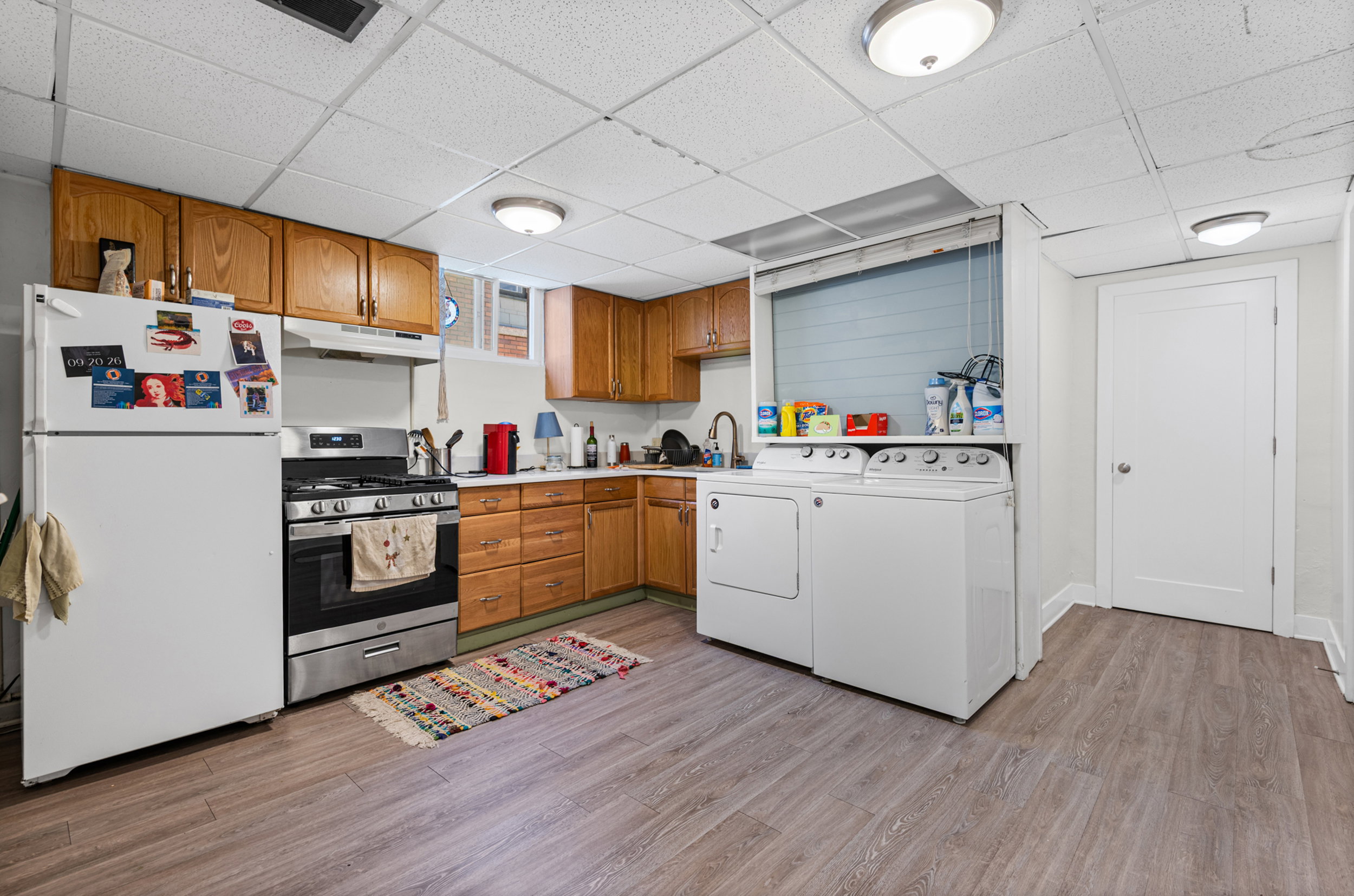 Kitchen and laundry area featuring wood-finish flooring, wood cabinetry, a stainless steel range, and a washer and dryer set