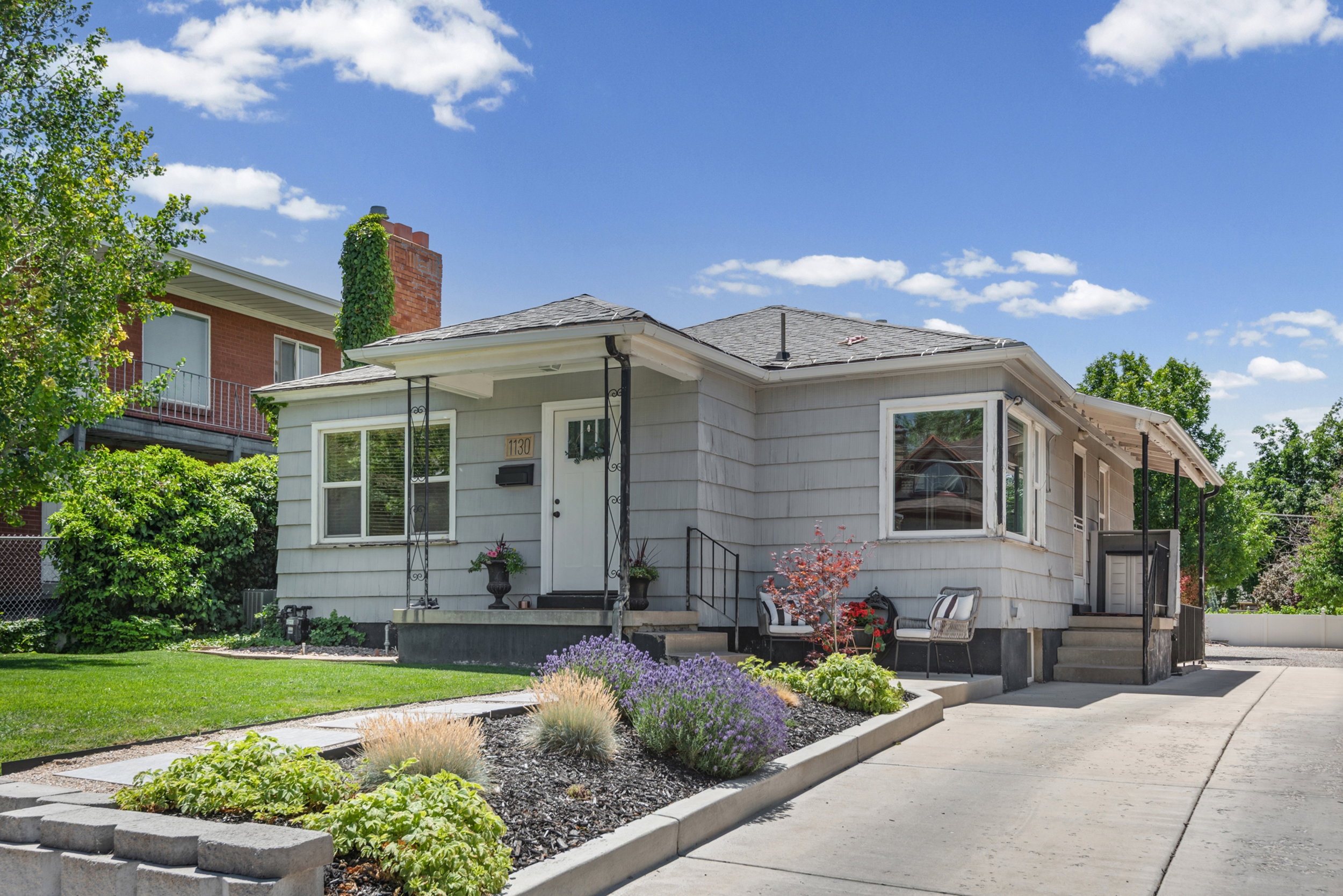 Single-story residence featuring light gray siding and a dark shingle roof