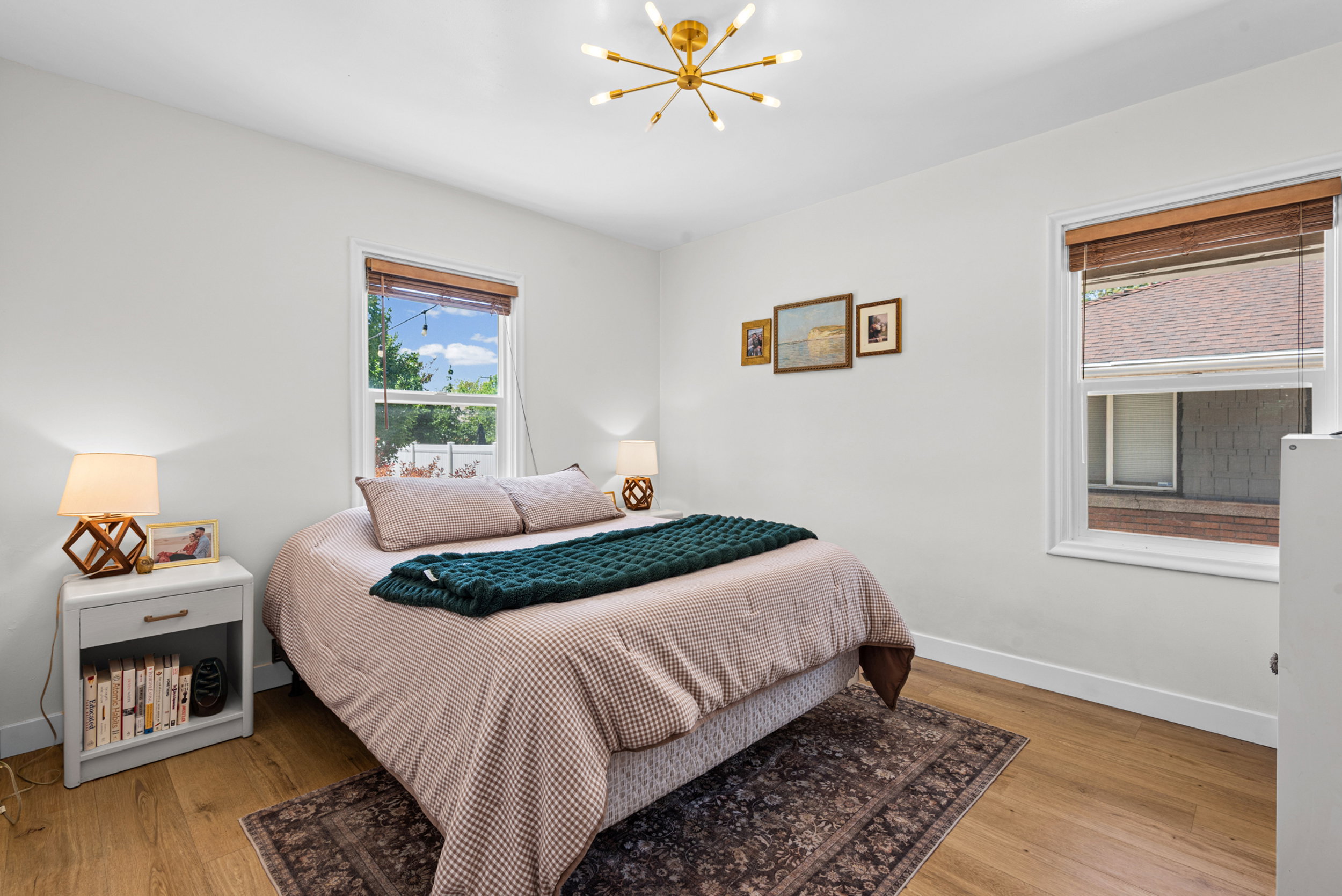 Room featuring wood-finish flooring, two windows with window treatments, and a contemporary ceiling light fixture