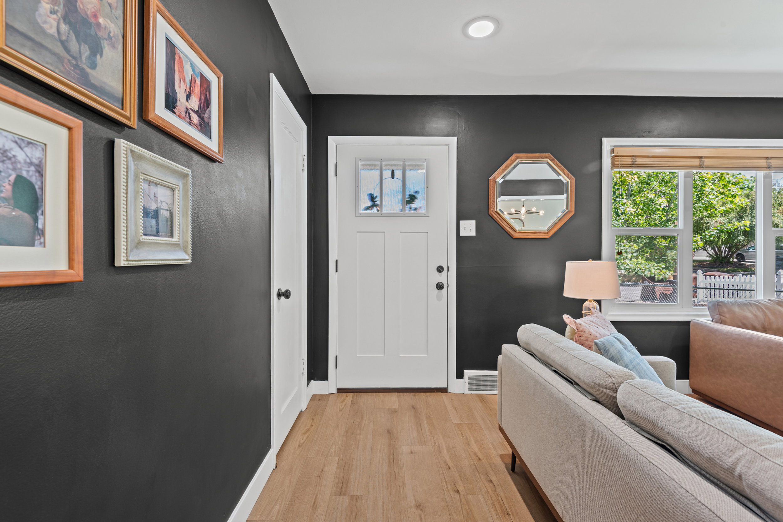 Entryway featuring wood-finish flooring, a white paneled door with glass inserts, and contrasting dark walls