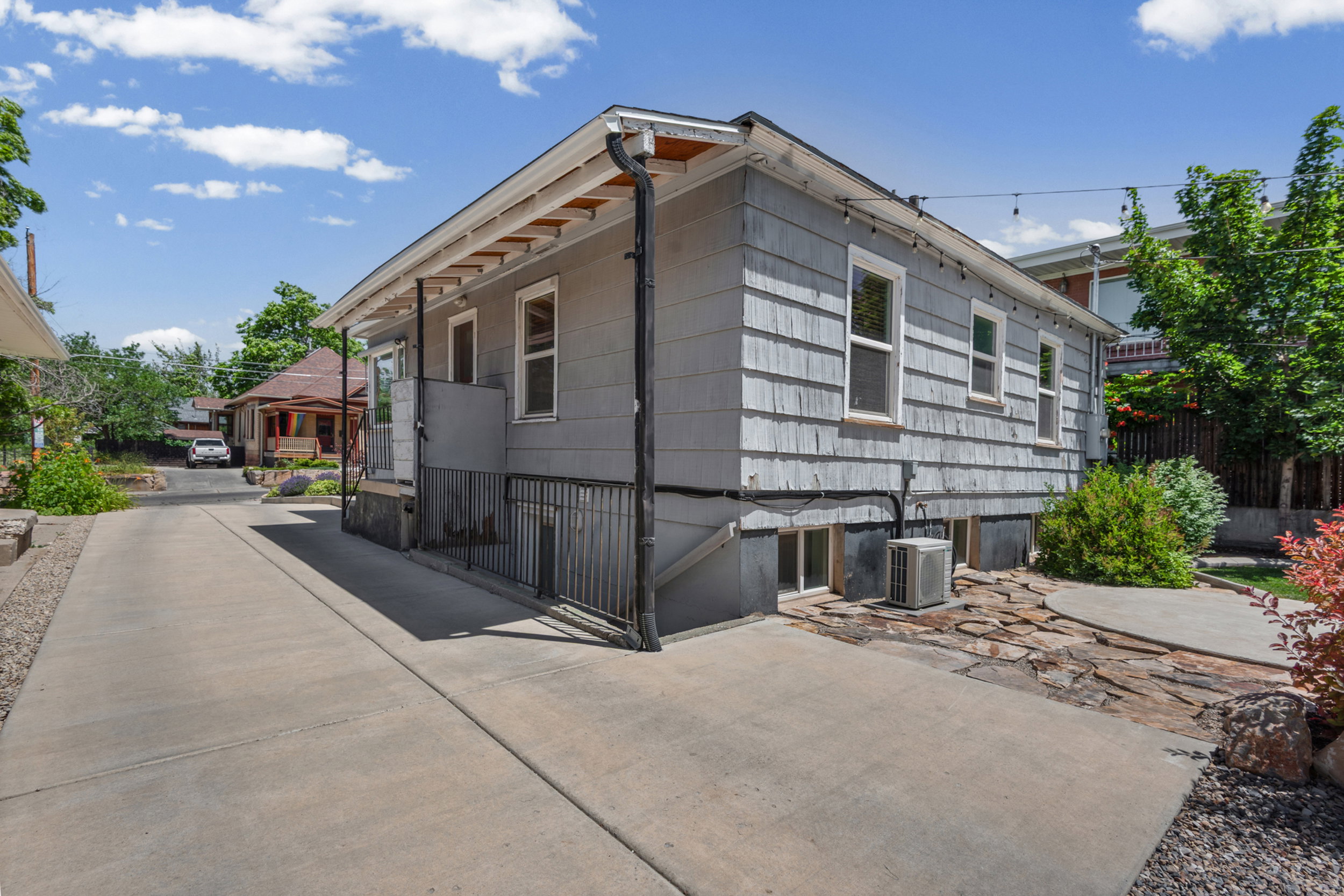 Side exterior featuring shingle siding, multiple windows, and a paved driveway