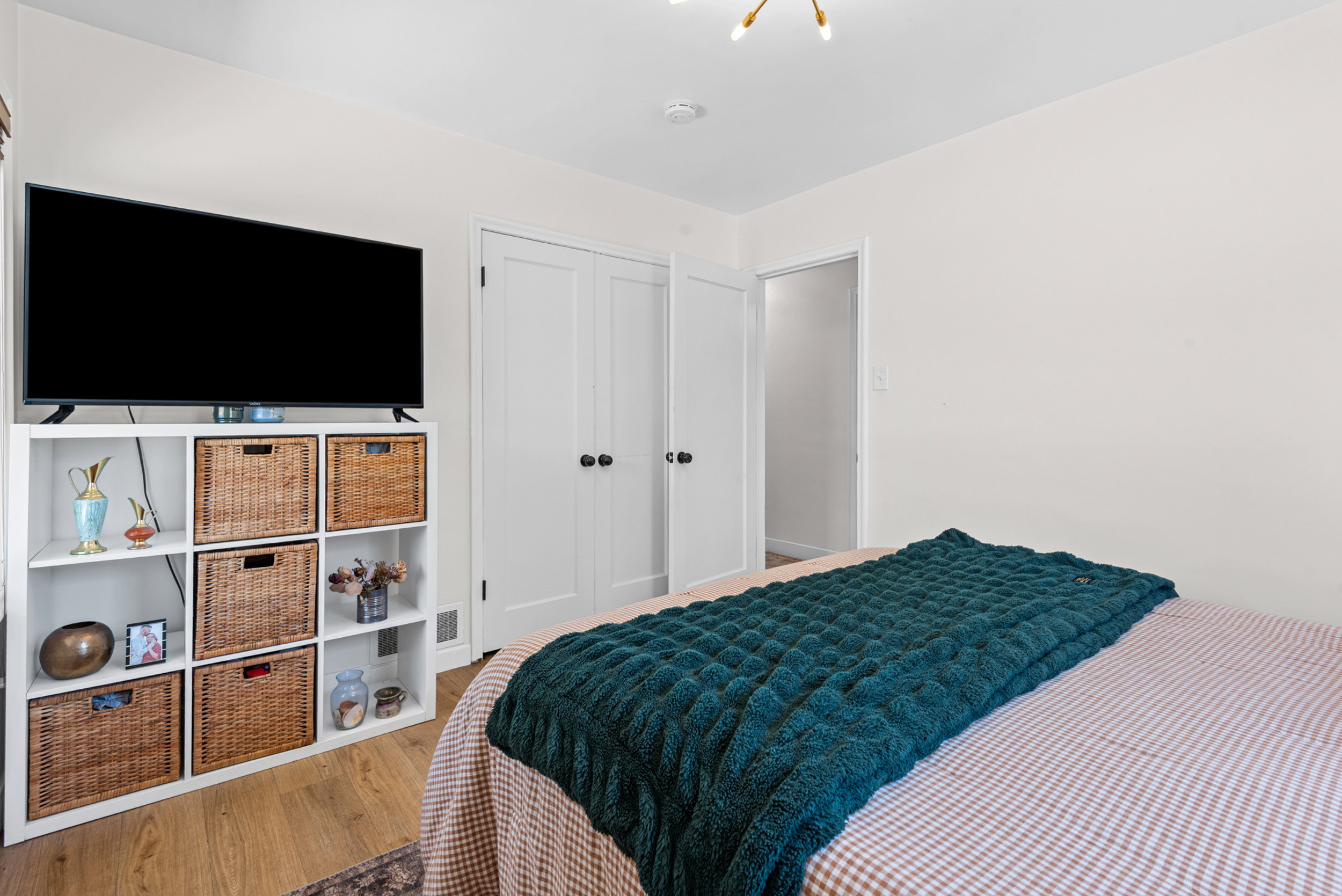 Bedroom featuring wood-finish flooring, white walls, and a modern ceiling light fixture