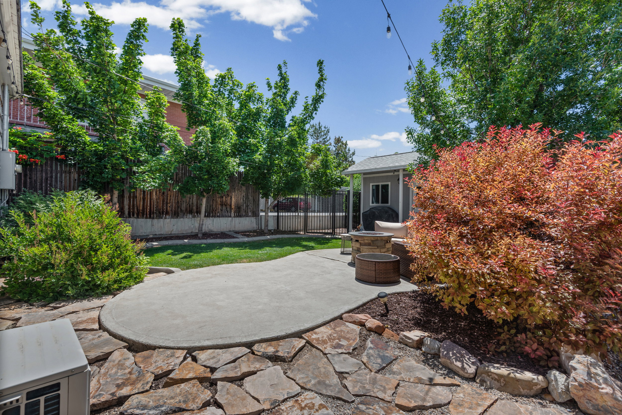 Expansive backyard featuring a curved concrete patio, natural stone flagstone landscaping, and a manicured lawn