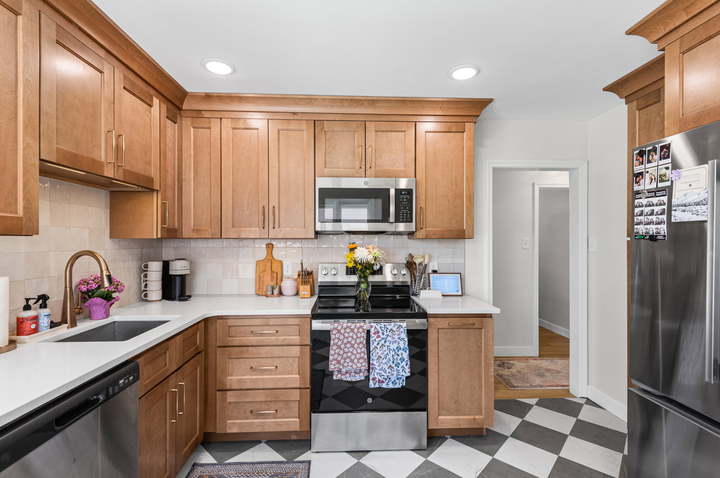 Kitchen featuring wood-finish cabinetry, stainless steel appliances, white countertops, a subway tile backsplash, and checkered flooring
