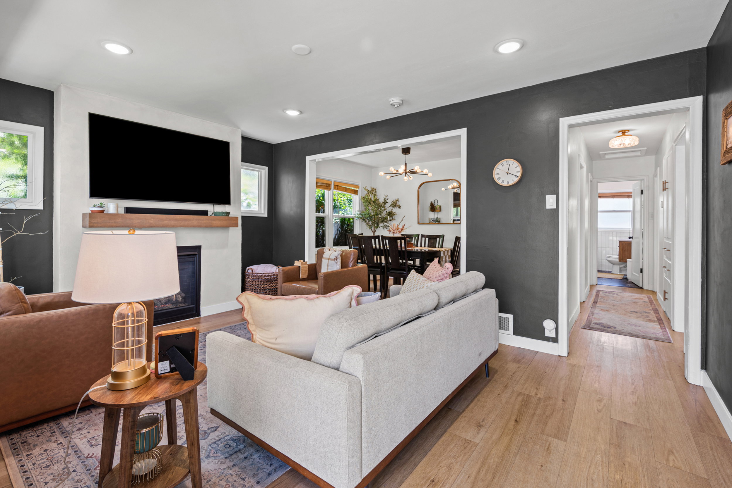 Living area featuring light wood-finish flooring, recessed lighting, and a fireplace with a light-toned mantel and wood shelf