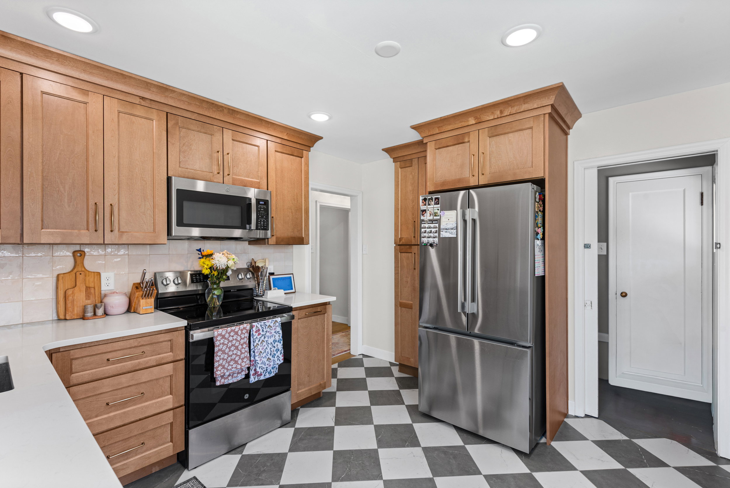 Kitchen featuring light wood cabinetry, stainless steel appliances, white countertops, and a checkered tile floor