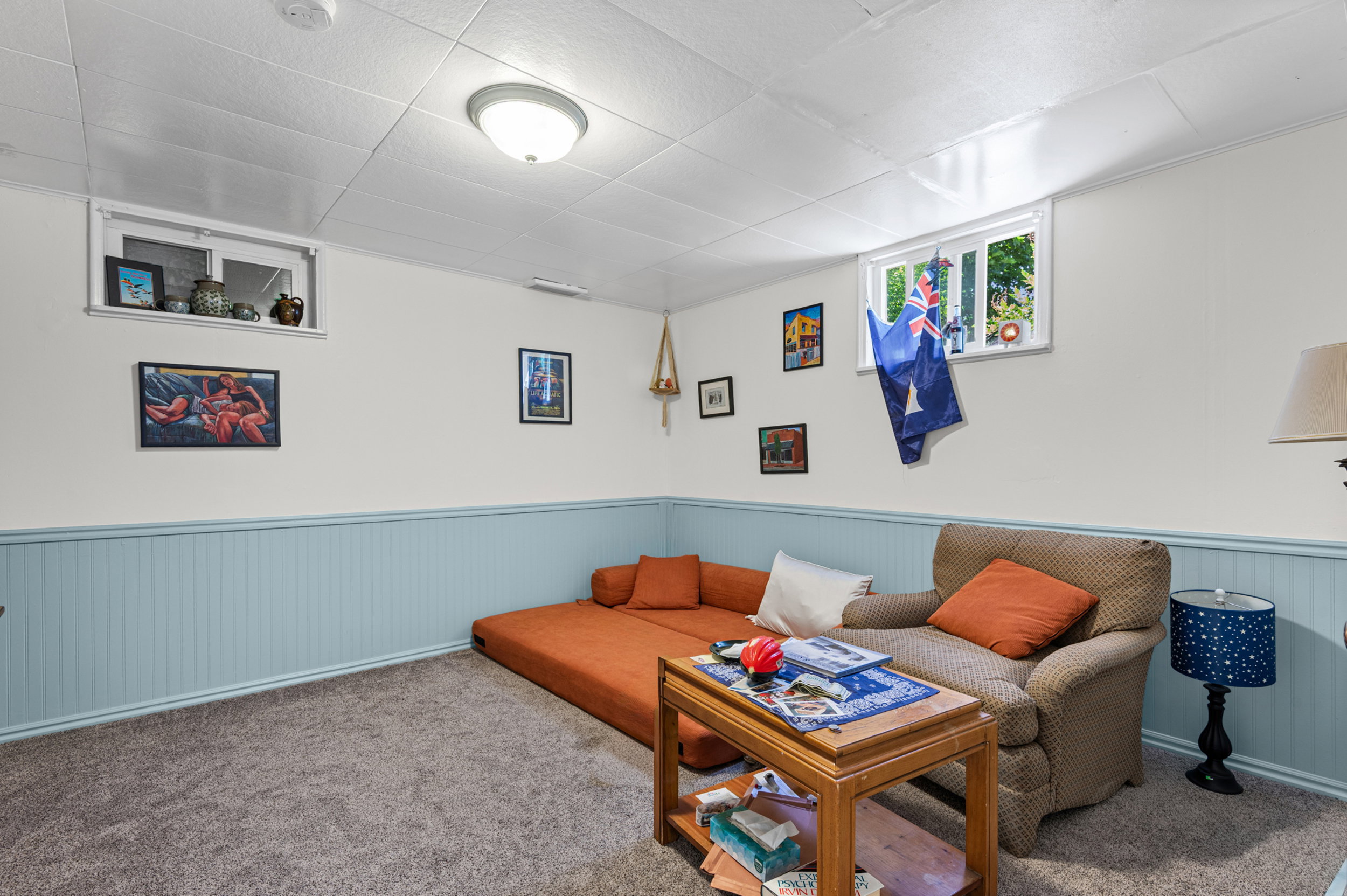Carpeted room featuring light blue wainscoting, white walls, and a white tile ceiling