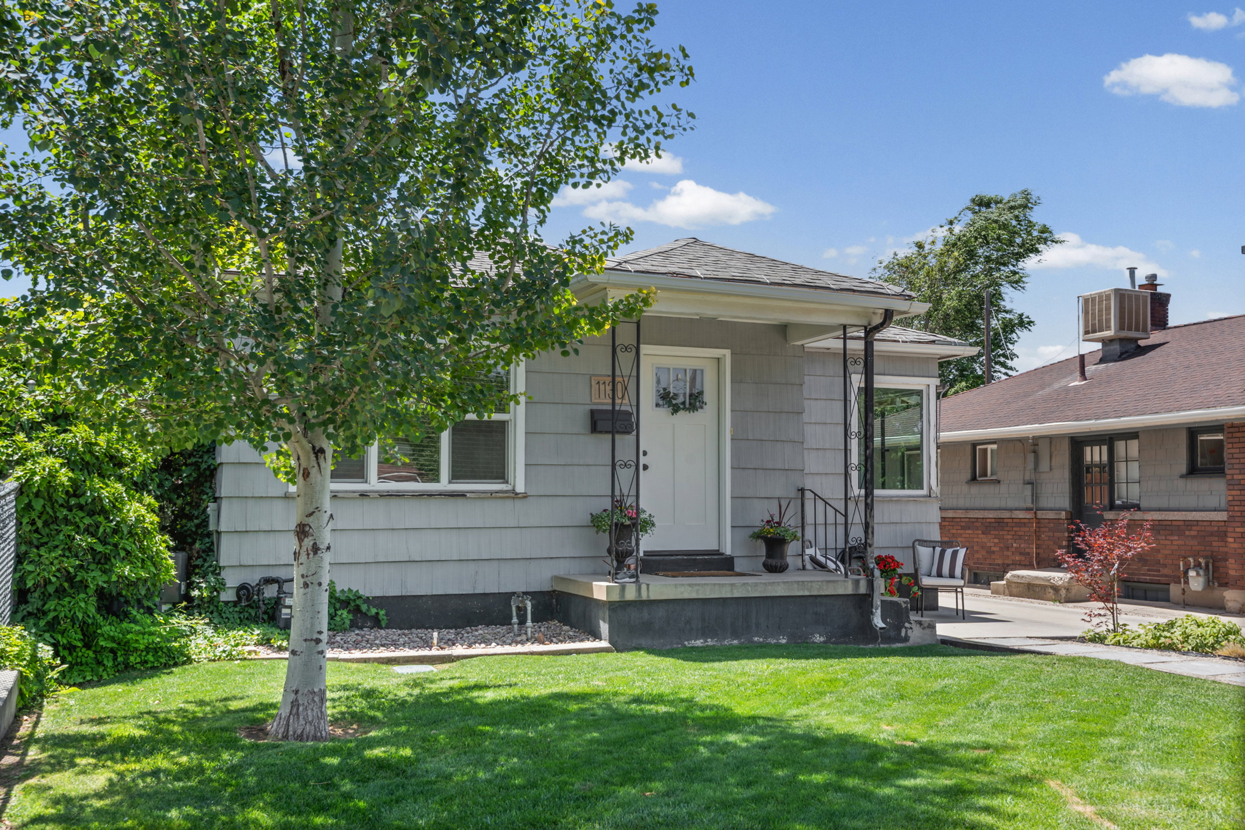 Single-story residence featuring light gray horizontal siding and a dark gray foundation