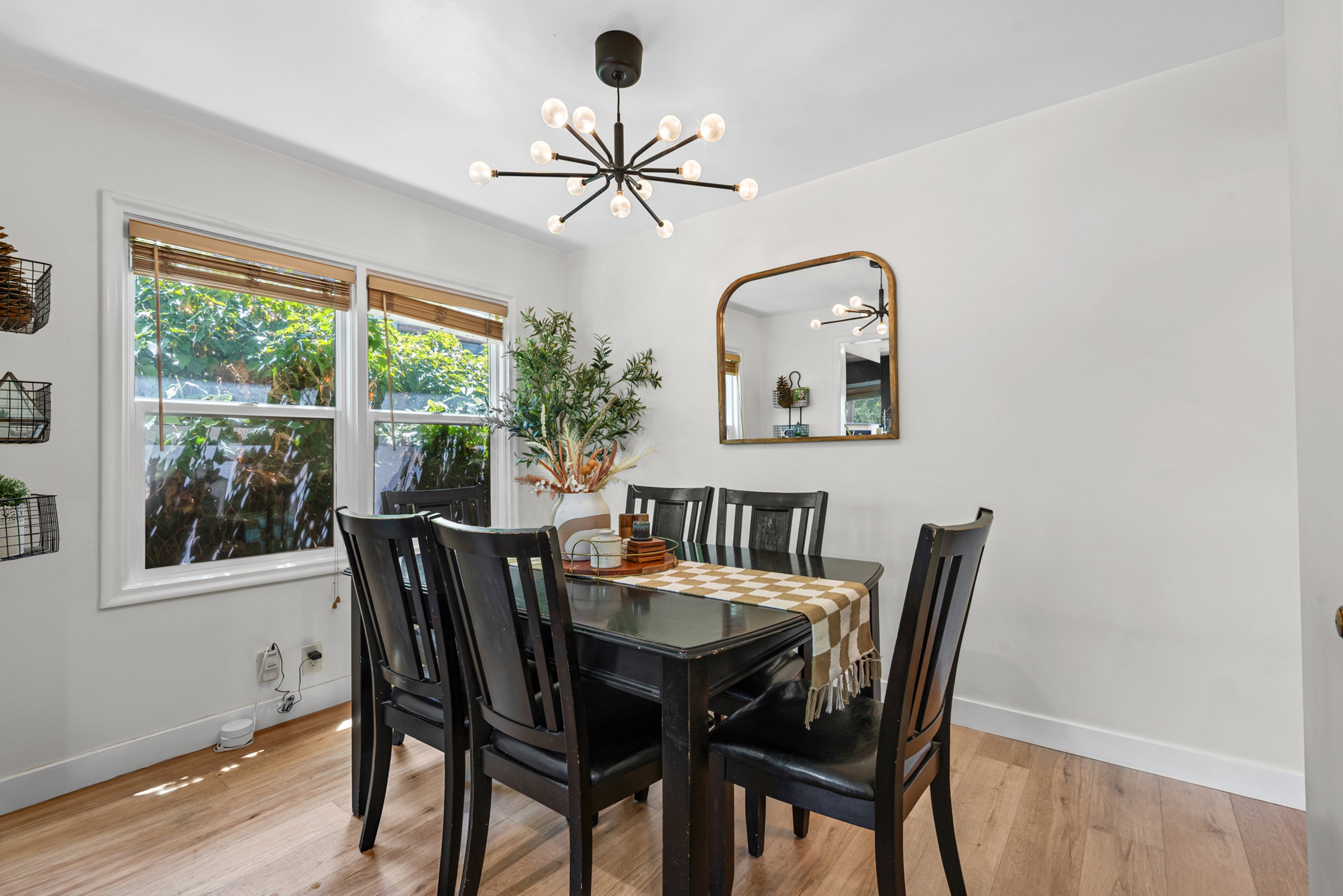 Dining area featuring warm wood-finish flooring, white walls, and a contemporary sputnik chandelier