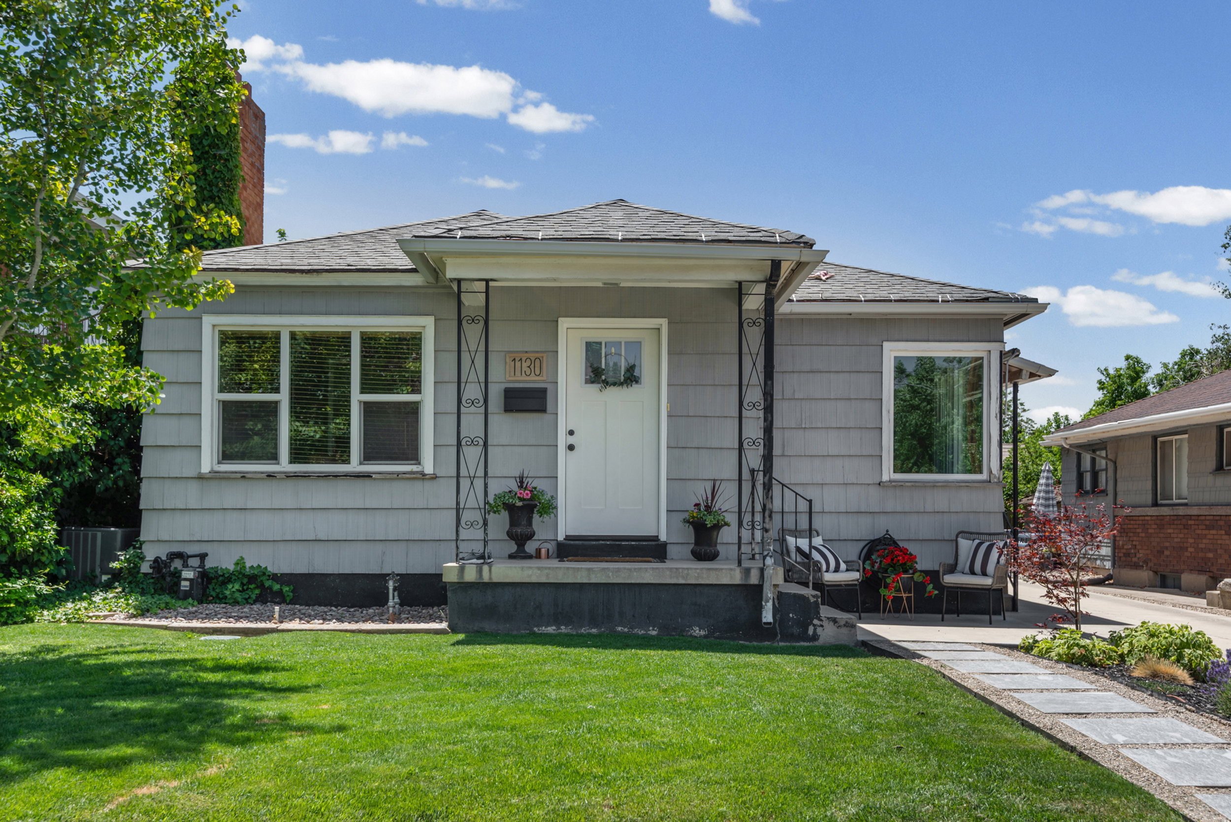 Gray siding exterior with white trim windows and a covered porch entry