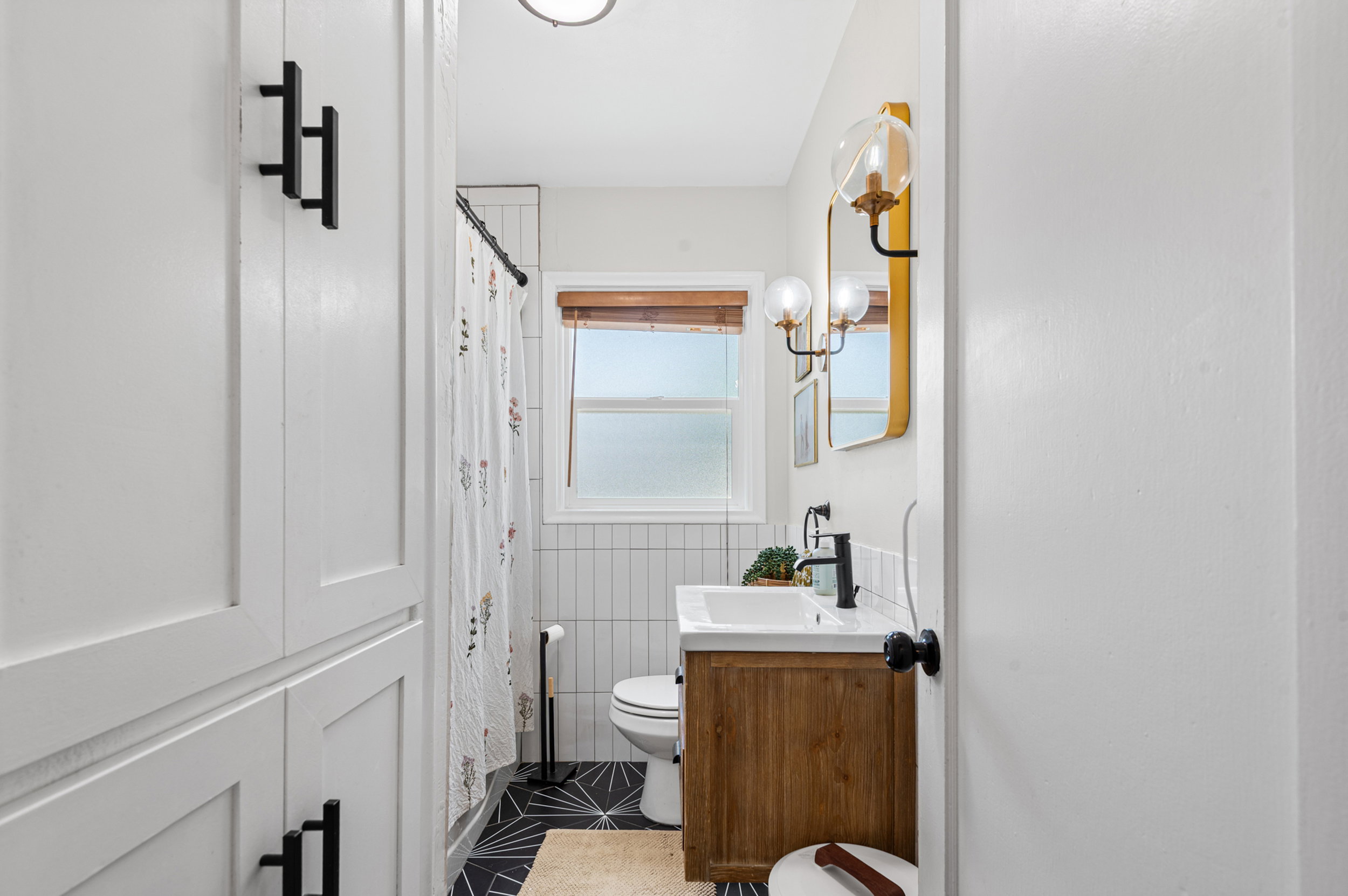 Bathroom featuring a wood-finish vanity with an undermount sink, matte black faucet, and a gold-framed mirror