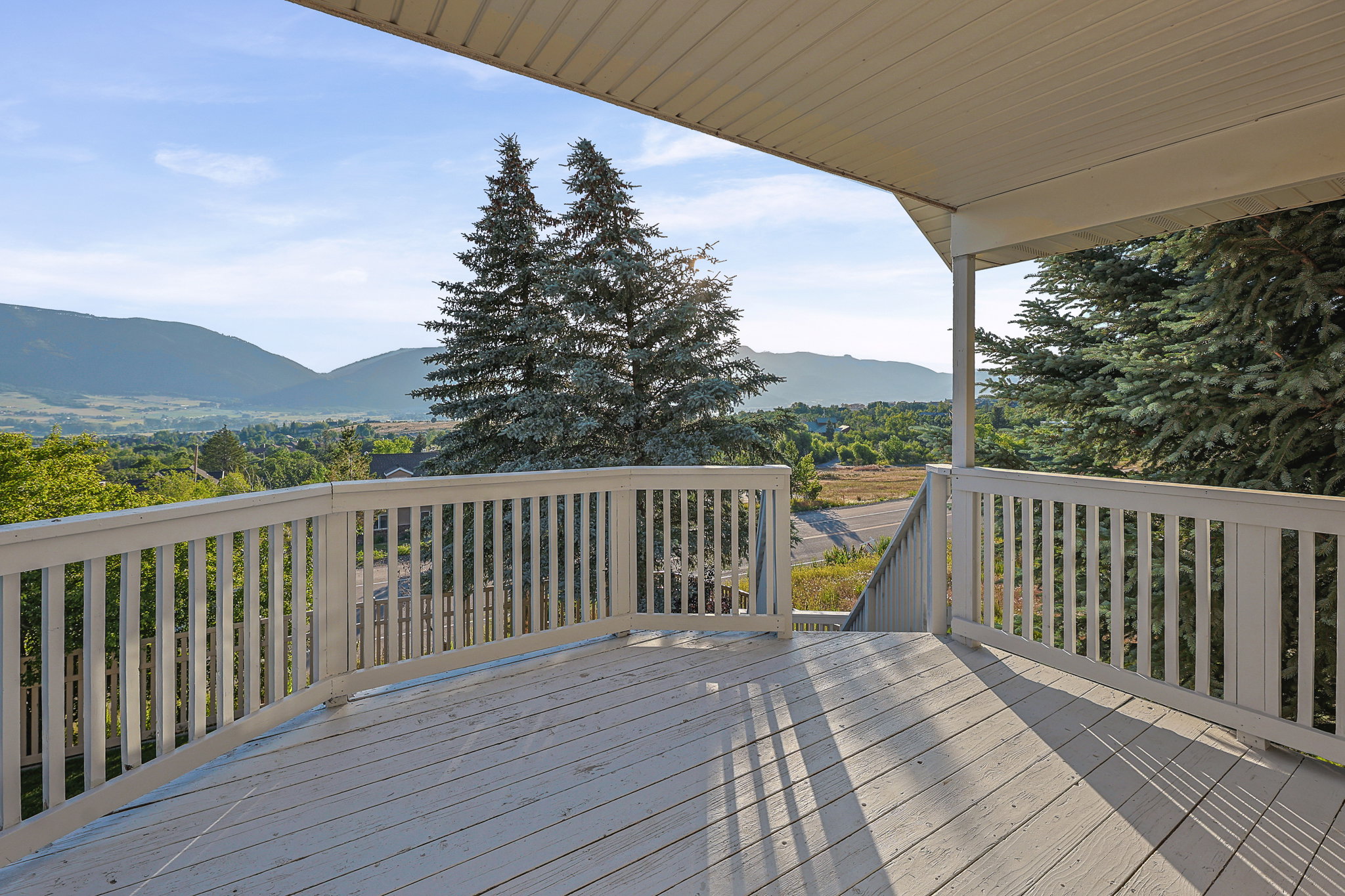 Spacious exterior deck with white painted railings and a sheltered overhead structure