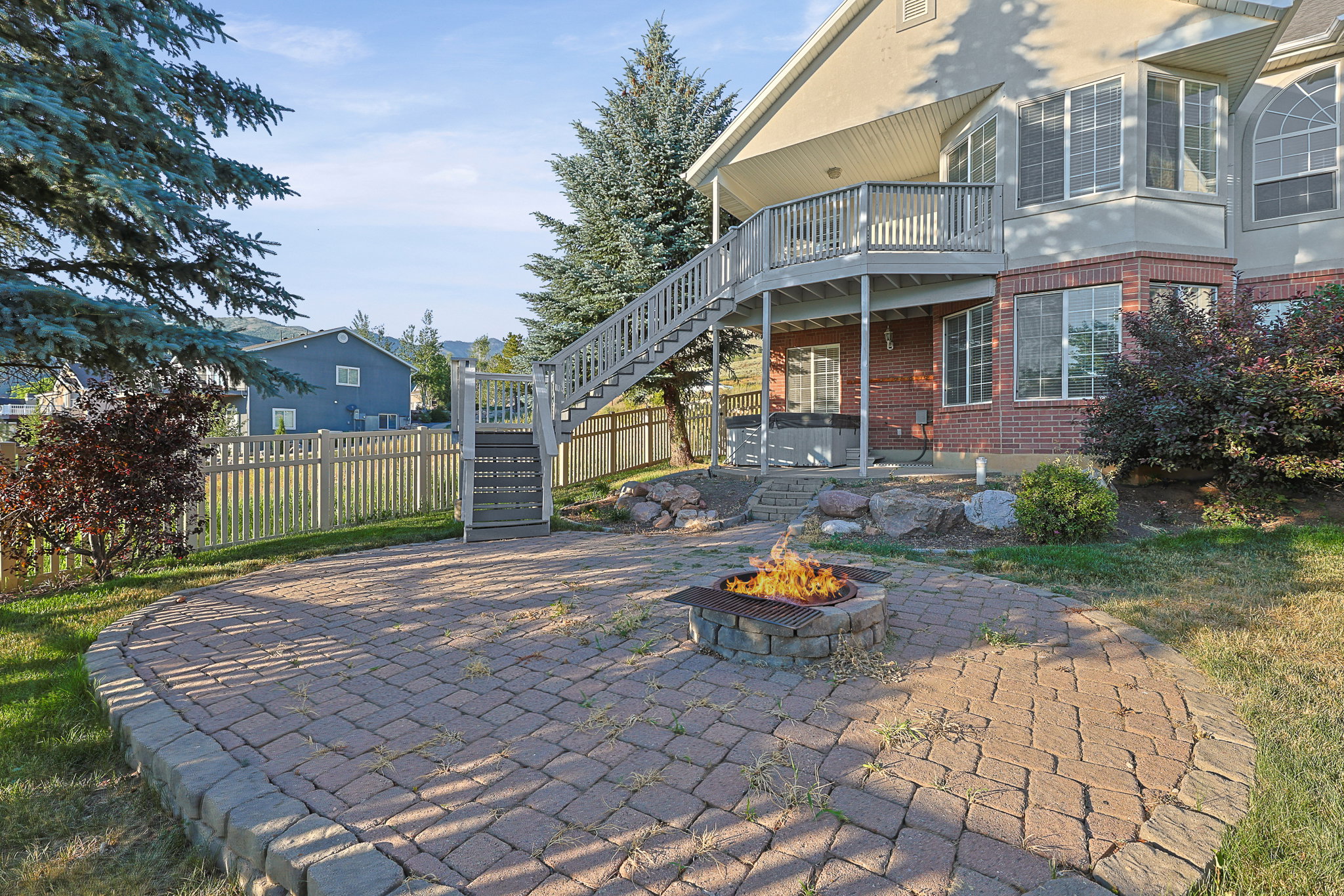 Paved patio featuring a stone fire pit, bordered by a retaining wall