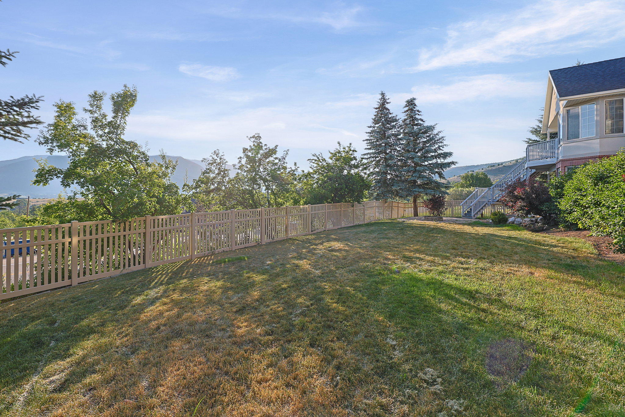 Expansive sloped lawn with a light-toned picket fence