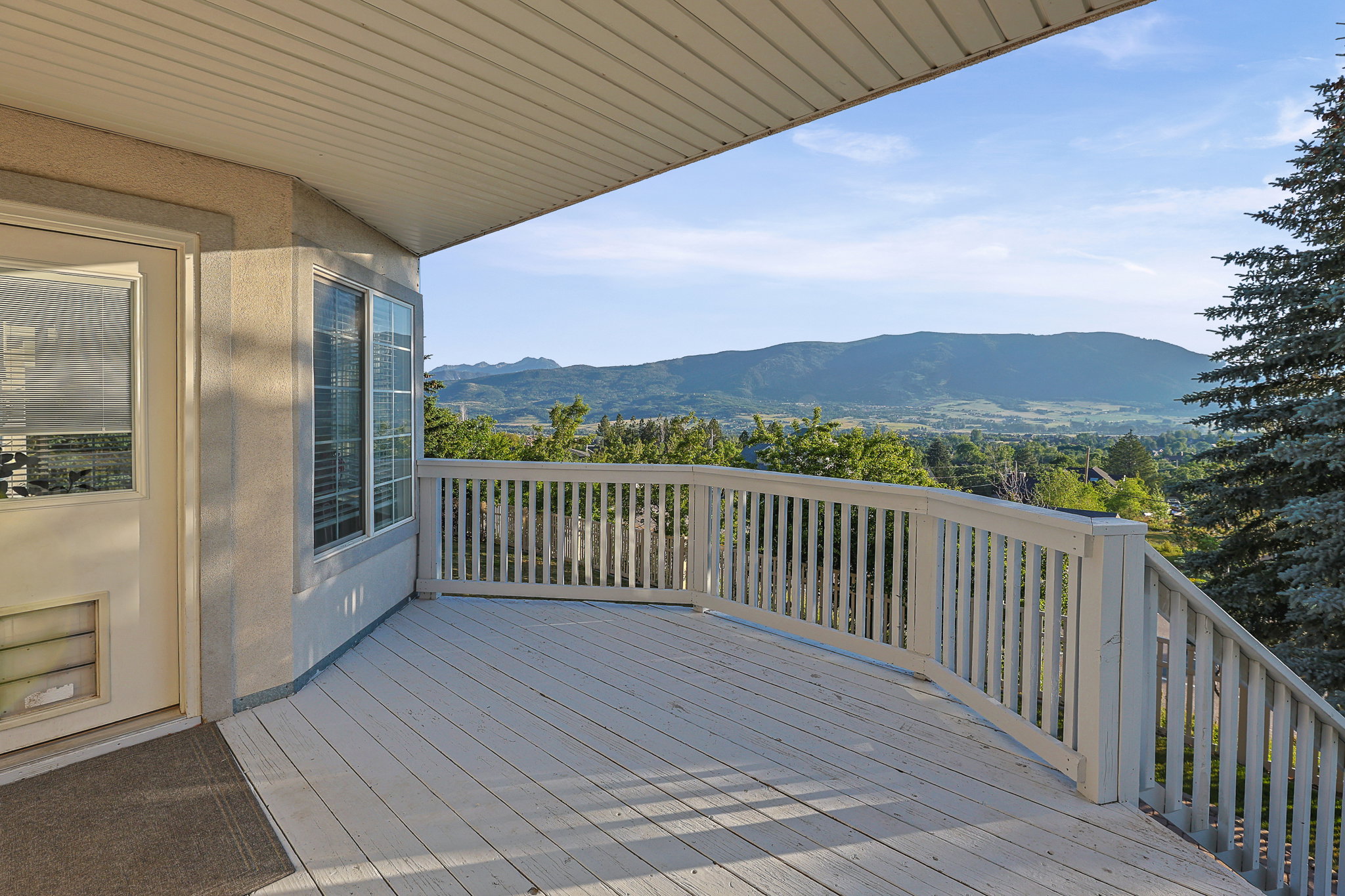 Expansive outdoor deck with white wood railings and a sweeping mountain backdrop