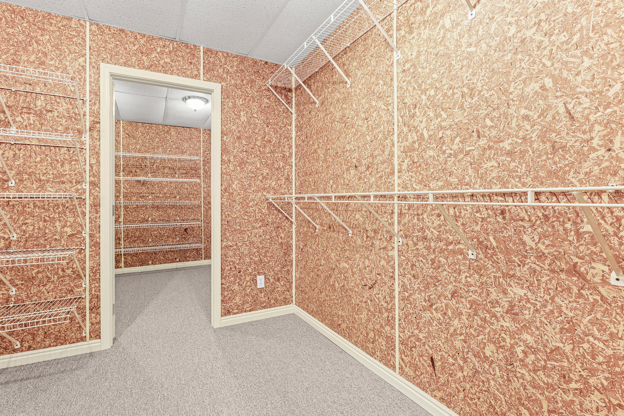 Spacious closet featuring abundant wire shelving, organized hanging rods, light-colored carpeting, and a textured wall finish
