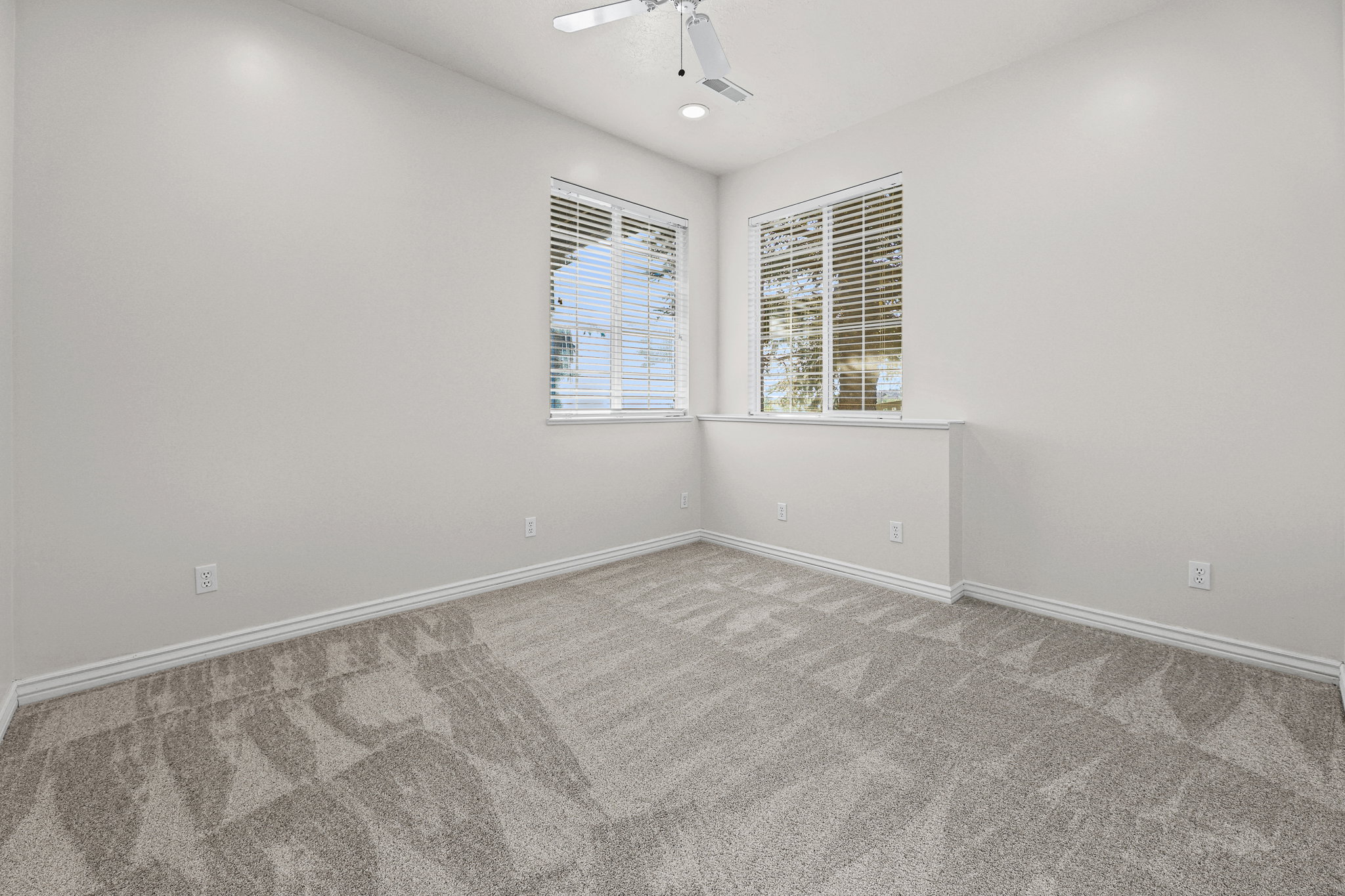 Carpeted room with a ceiling fan, recessed lighting, and two windows featuring blinds