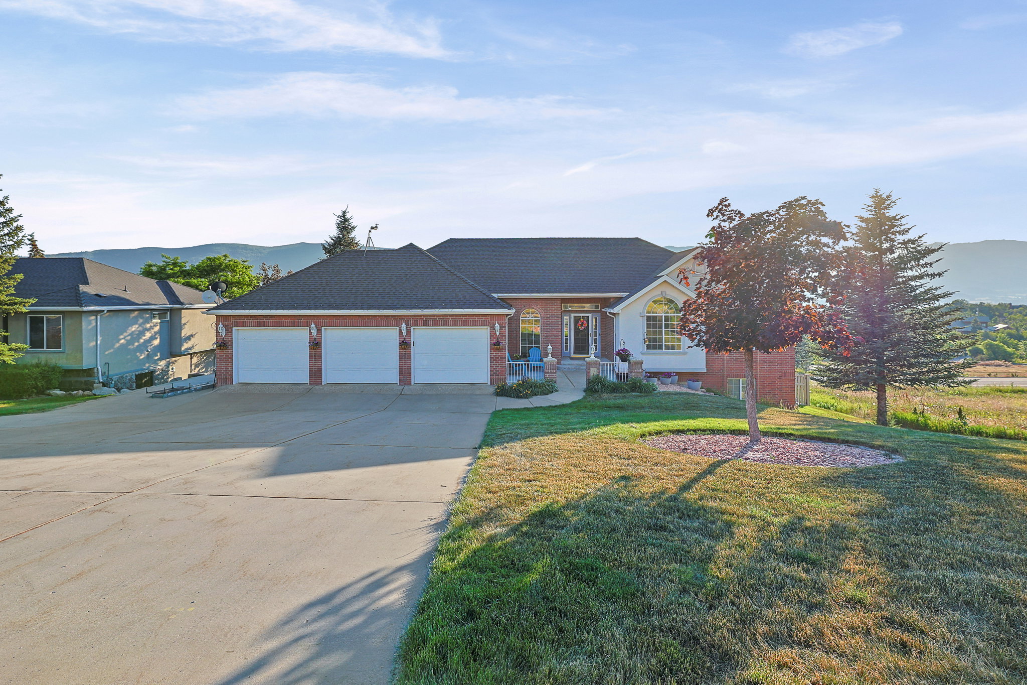 Brick and siding exterior featuring a three-car garage and a paved driveway