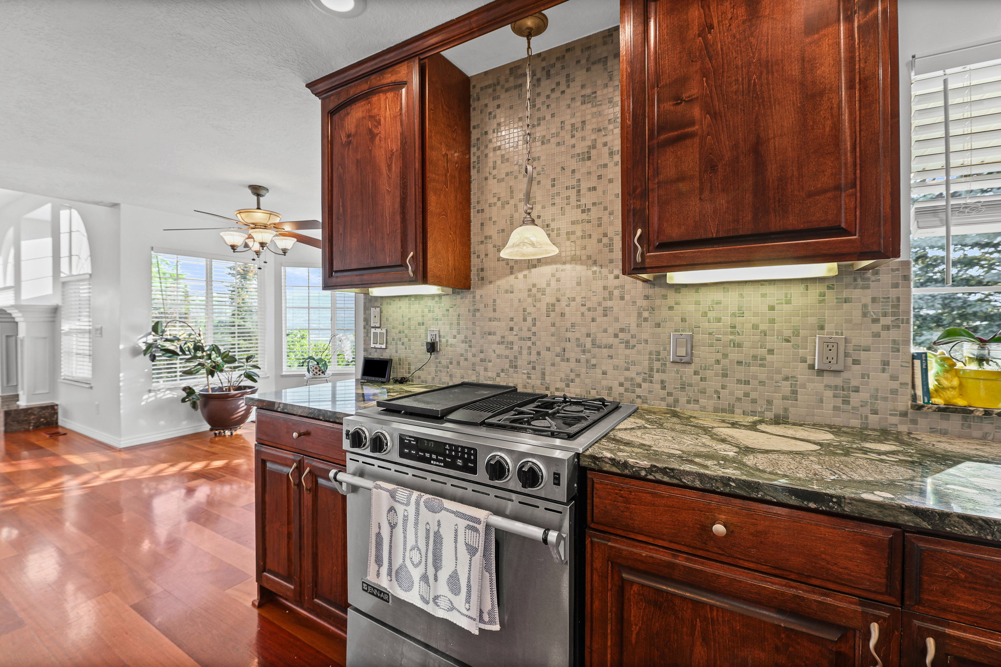 Stainless steel range with a built-in griddle, complemented by a mosaic tile backsplash and rich wood cabinetry
