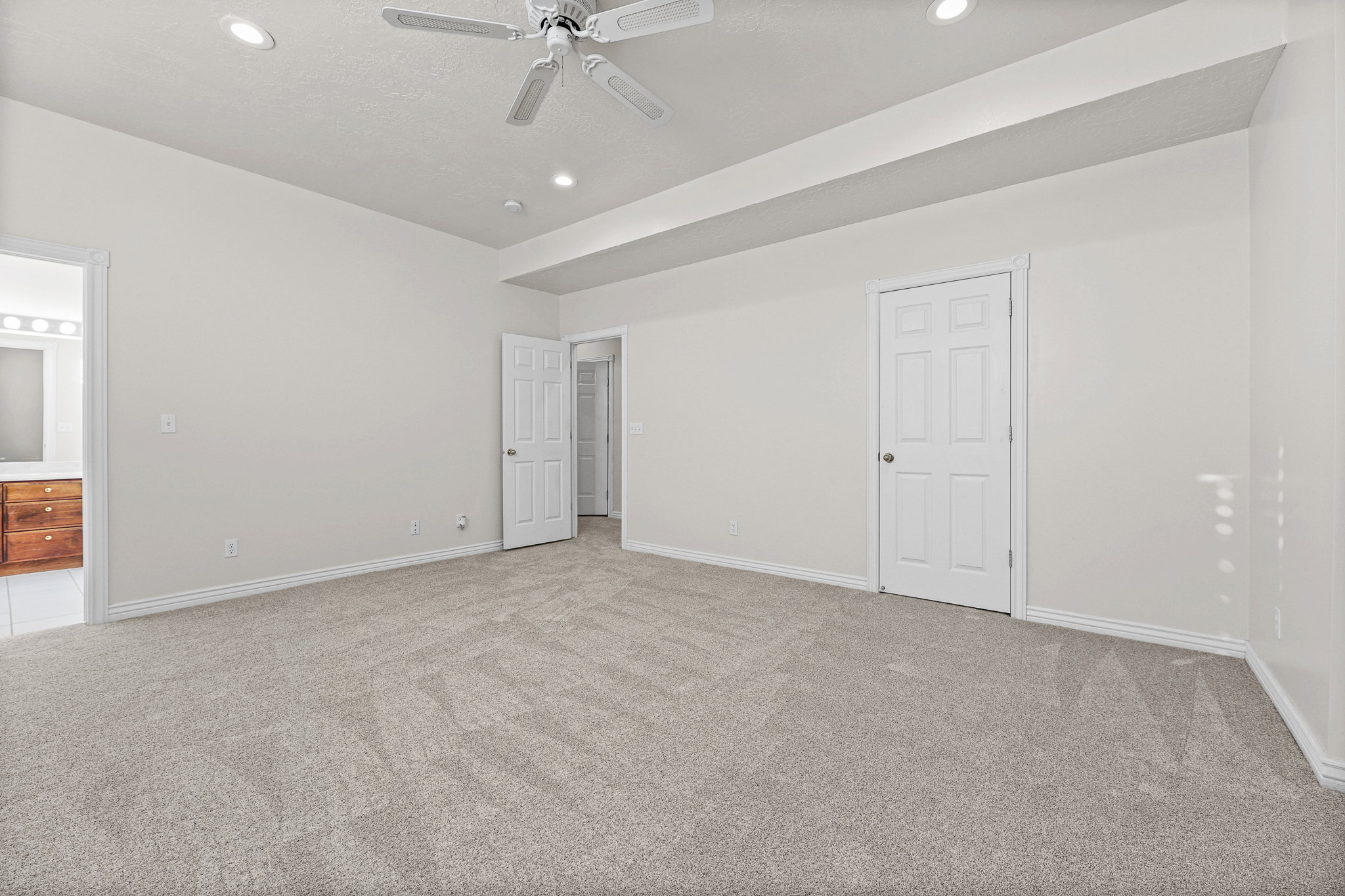 Spacious room featuring light-colored carpeting, recessed lighting, and a ceiling fan