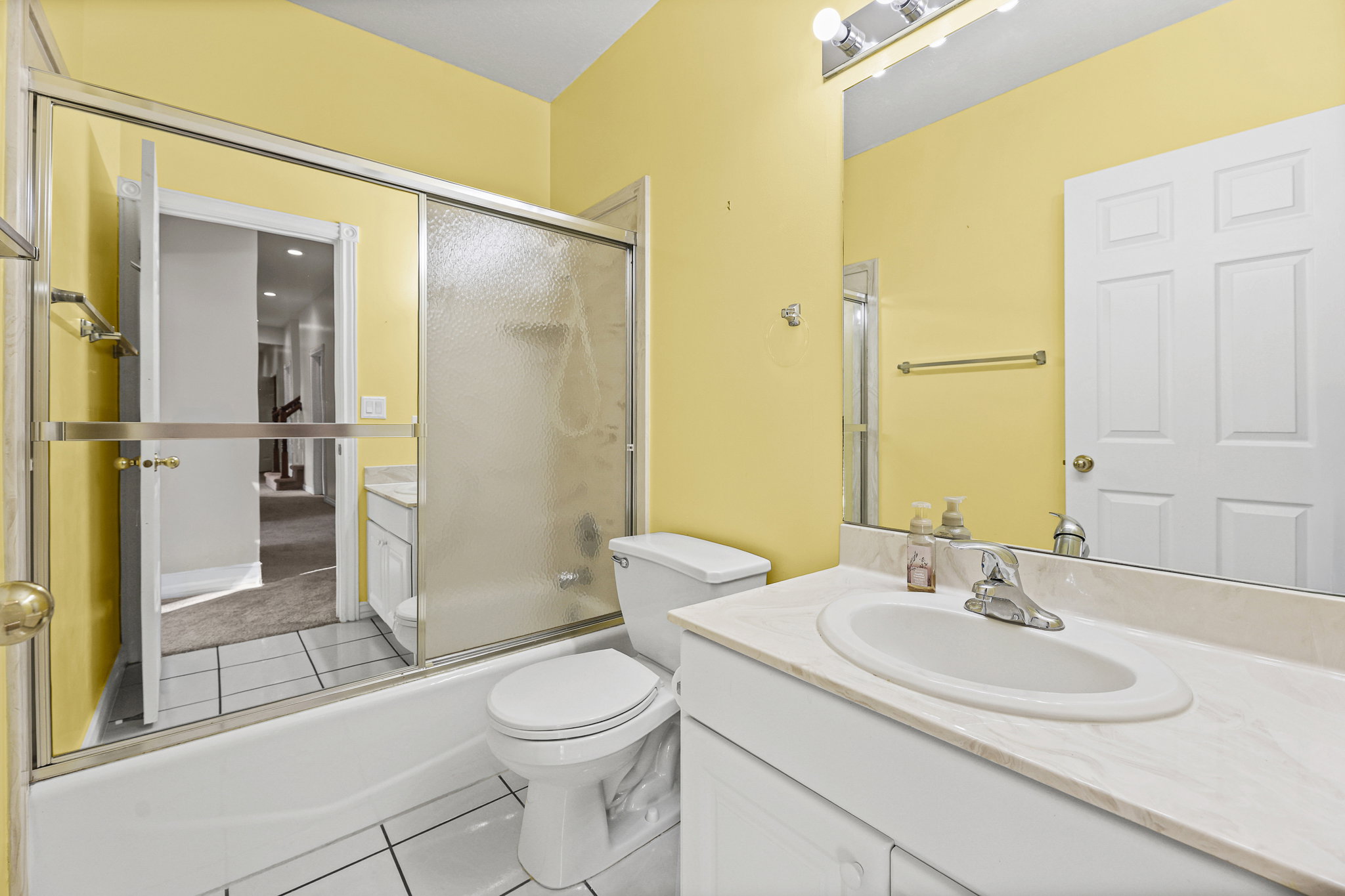 Bathroom featuring a white vanity with a built-in sink, an extended countertop, and a large mirror with overhead lighting