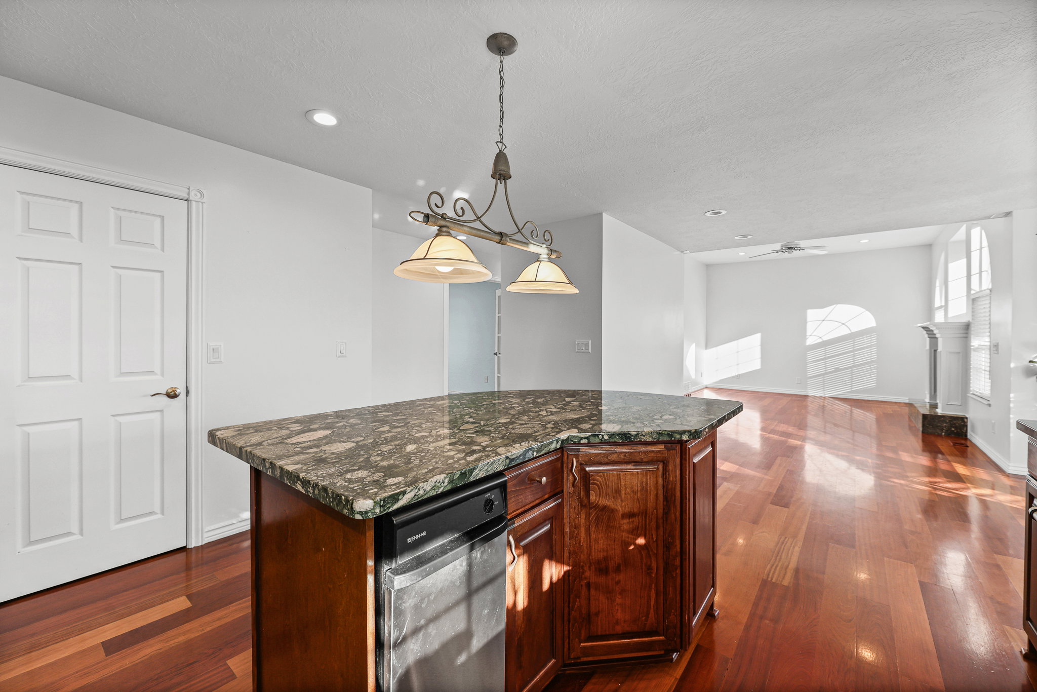 Kitchen island featuring a granite countertop, wood-finish cabinetry, and an integrated dishwasher