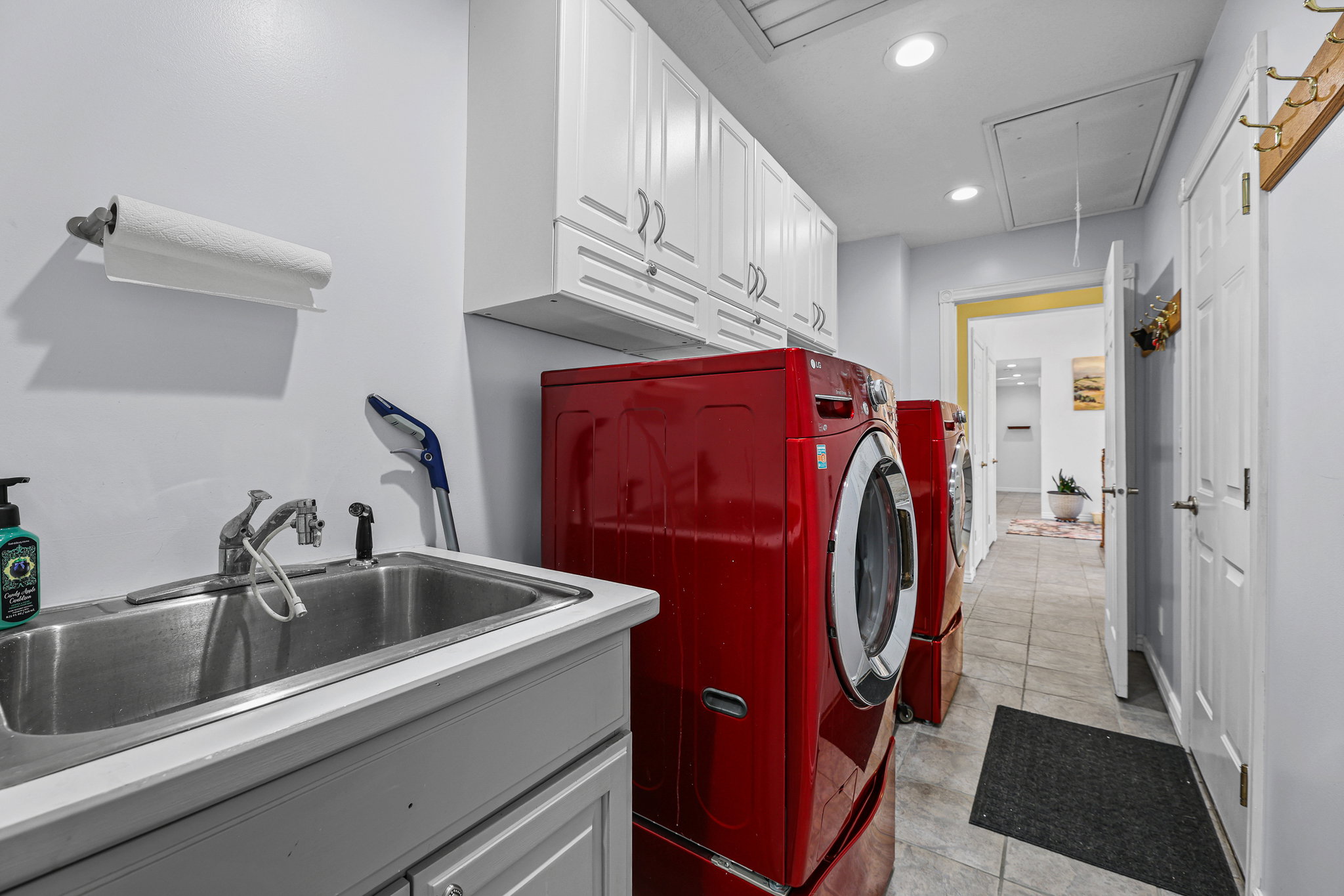 Dedicated laundry area featuring a utility sink, white cabinetry with silver hardware, and tiled flooring