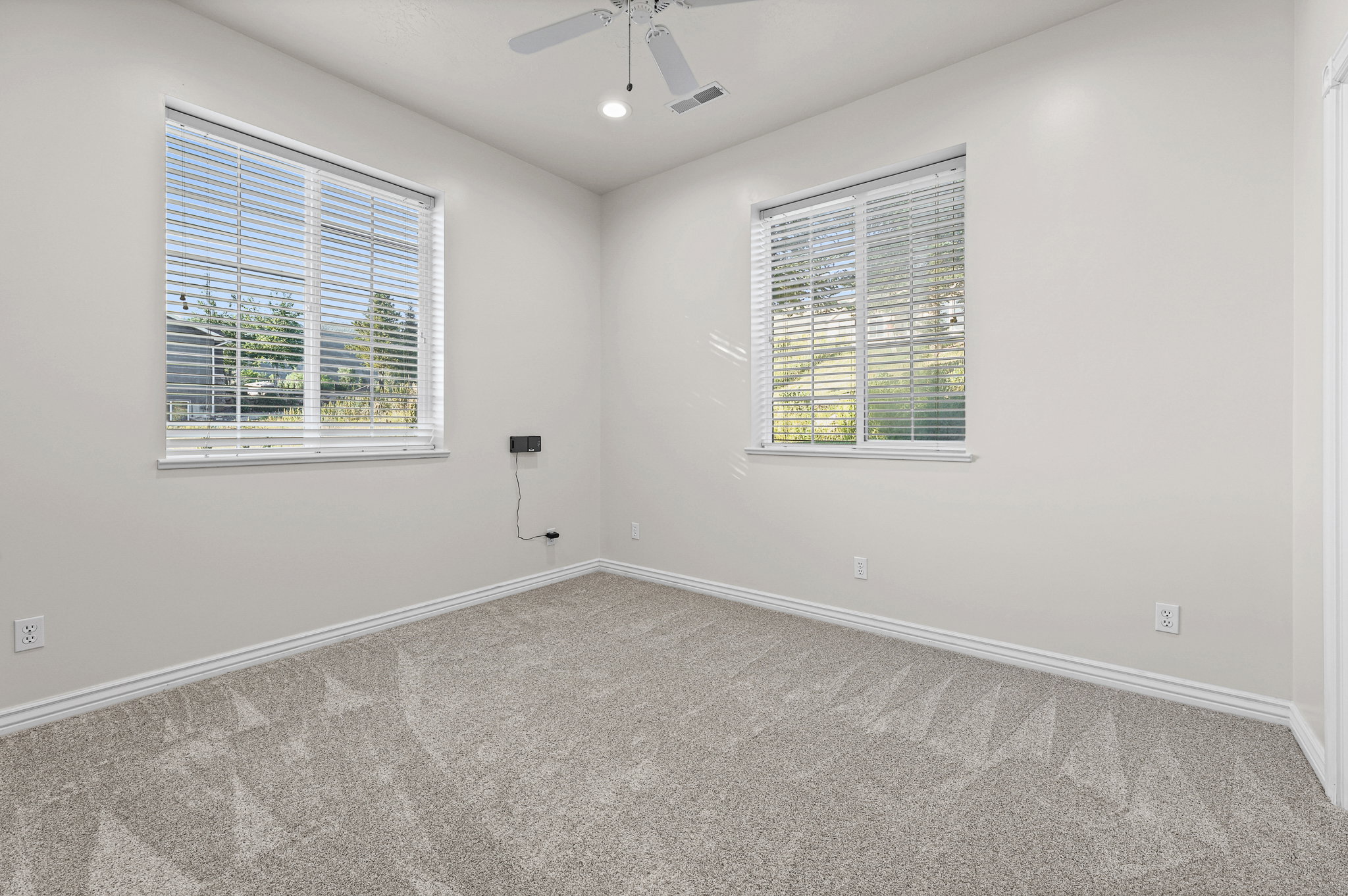 Room featuring neutral wall tones, two windows with blinds, a ceiling fan with integrated lighting, and light-toned carpeting