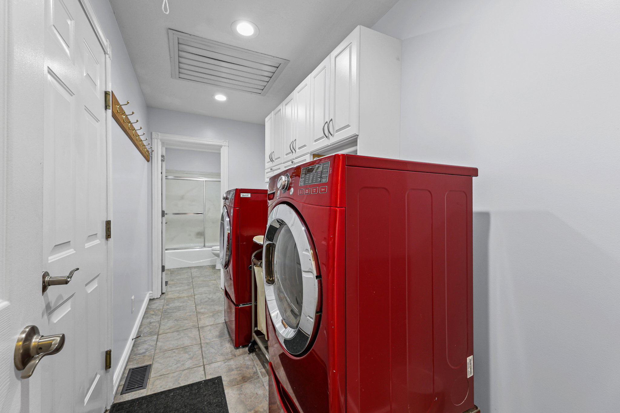 Dedicated laundry room featuring tile flooring, white cabinetry, recessed lighting, and a built-in hanging rack