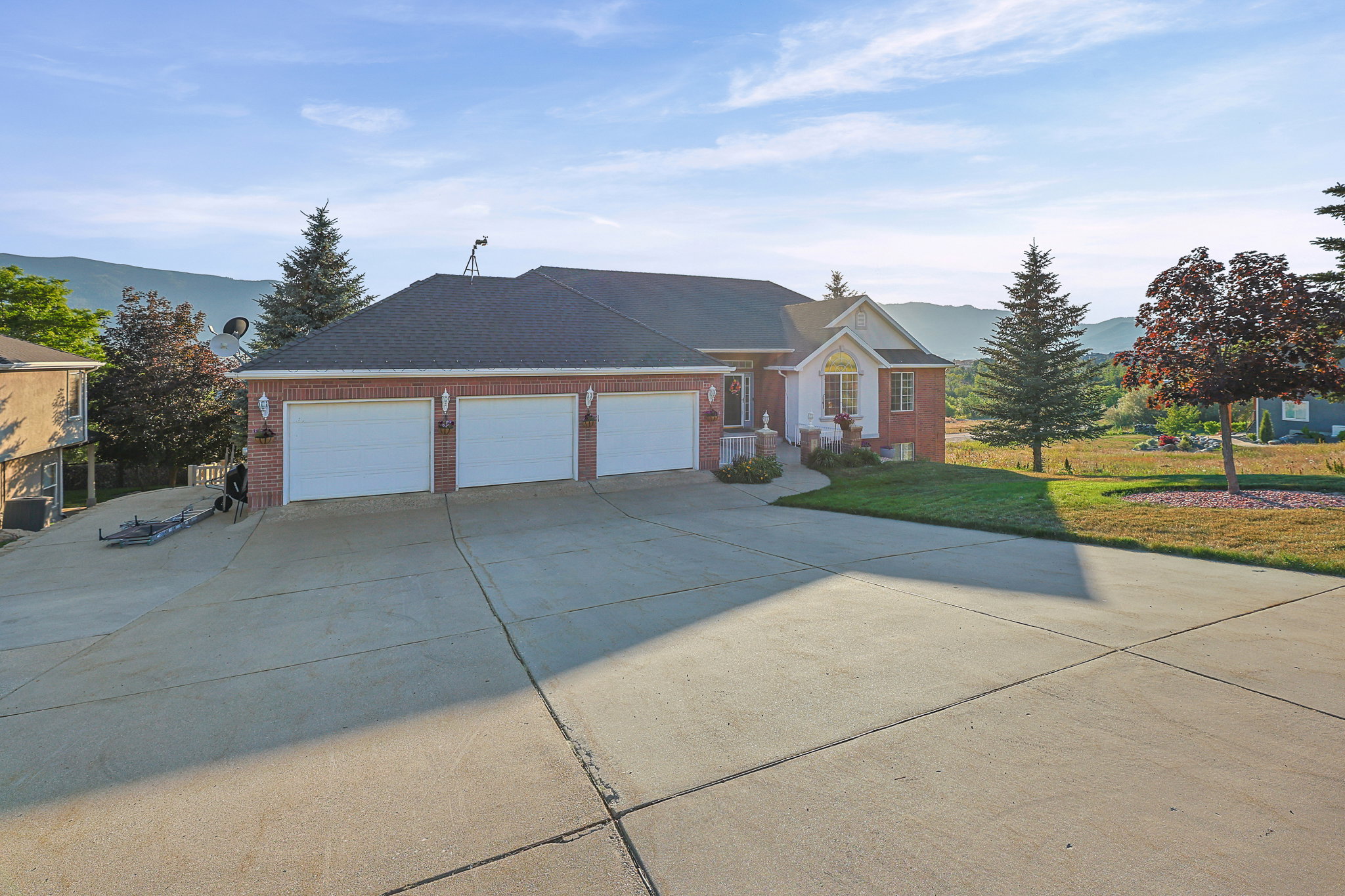 Brick exterior featuring a three-car garage and a concrete driveway