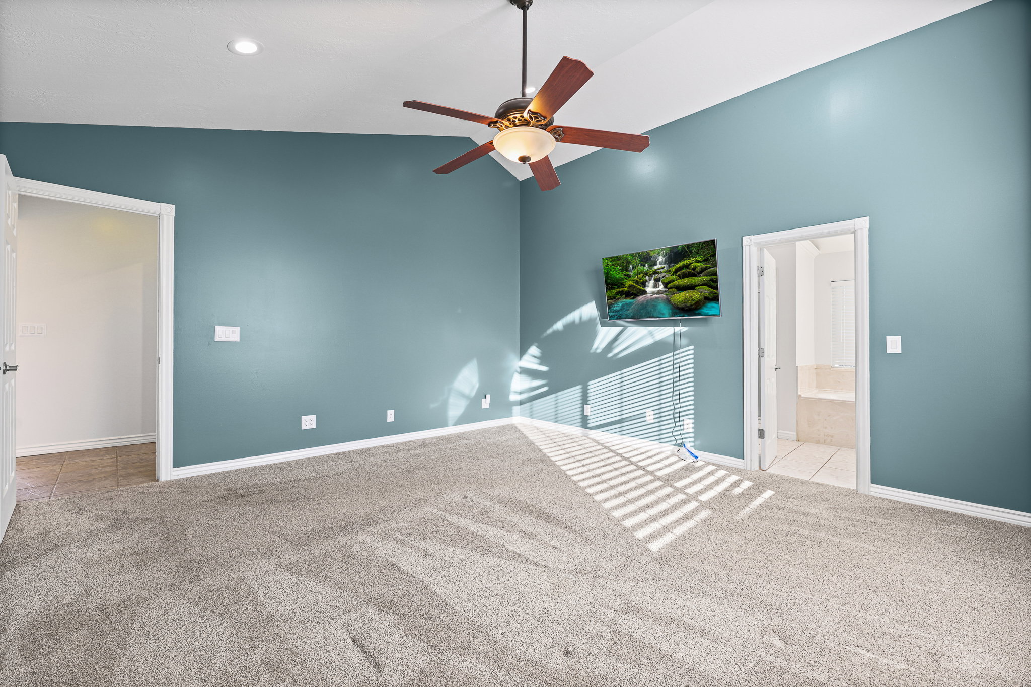 Carpeted room featuring a vaulted ceiling with a ceiling fan, recessed lighting, and teal-painted walls