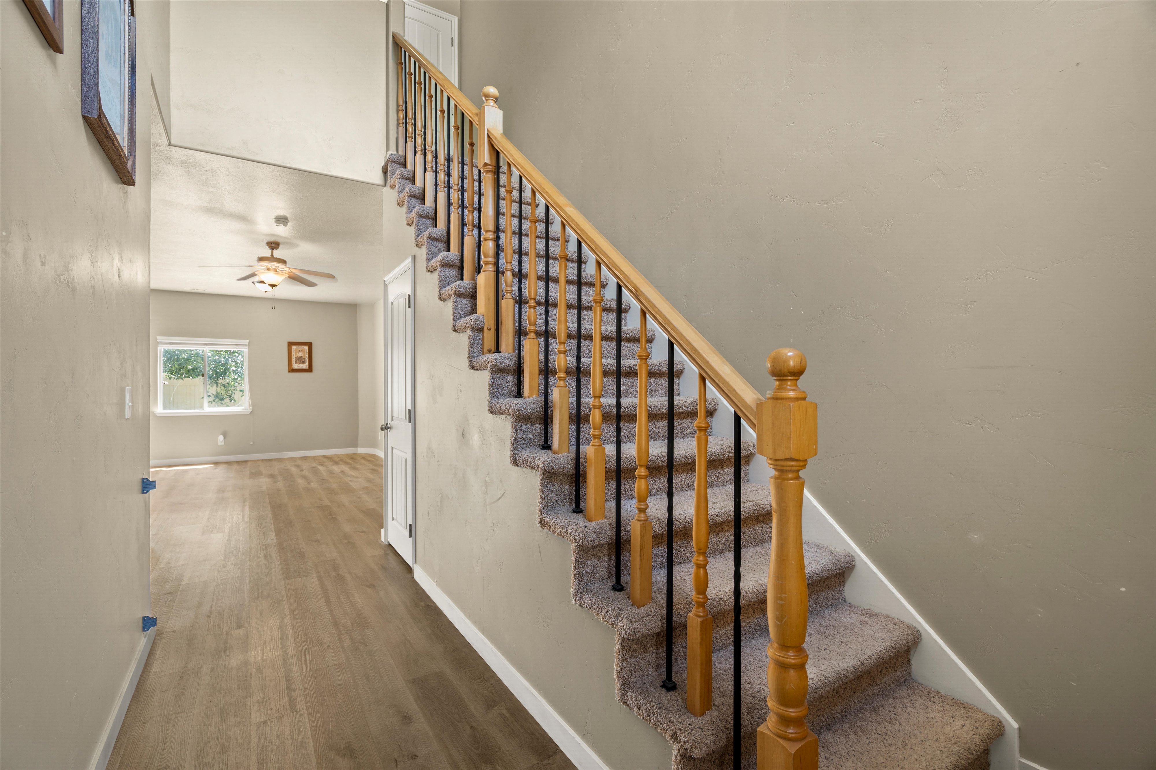 Carpeted staircase with wooden handrail and black metal balusters