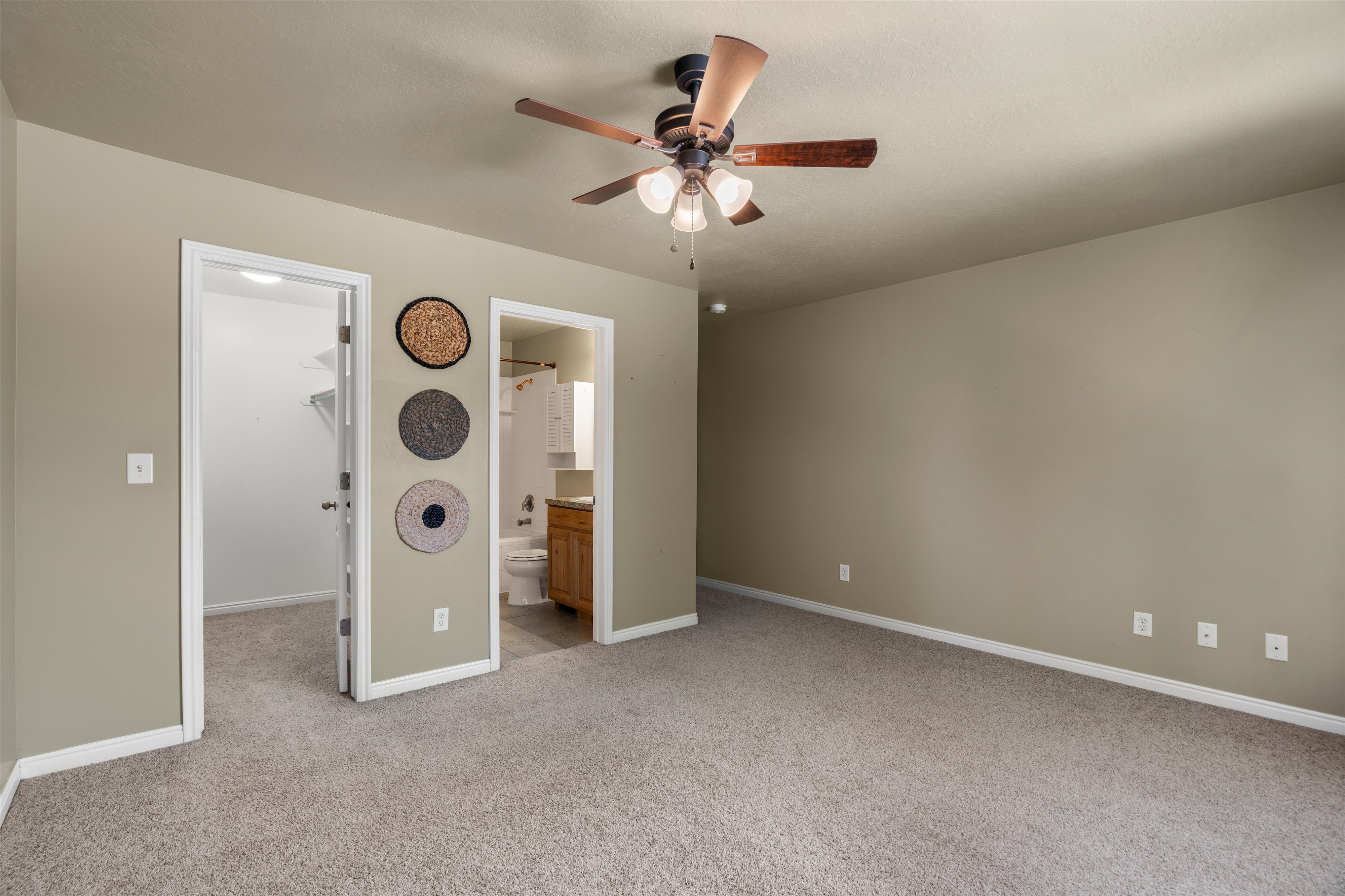 Carpeted room featuring a ceiling fan with integrated lighting, neutral wall tones, and white baseboards