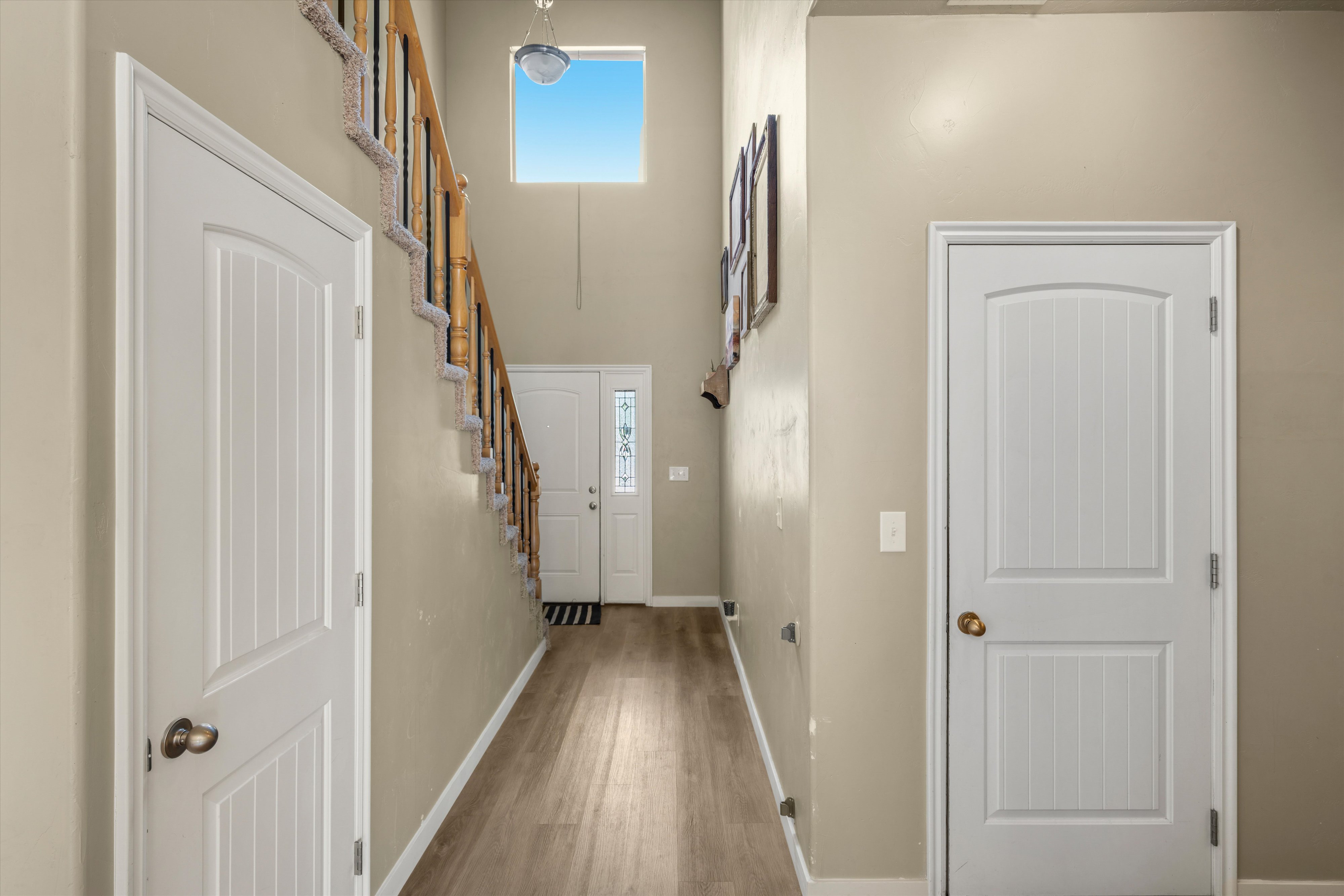 Two-story foyer featuring wood-finish flooring, a carpeted staircase with a wood handrail, and a high-set window