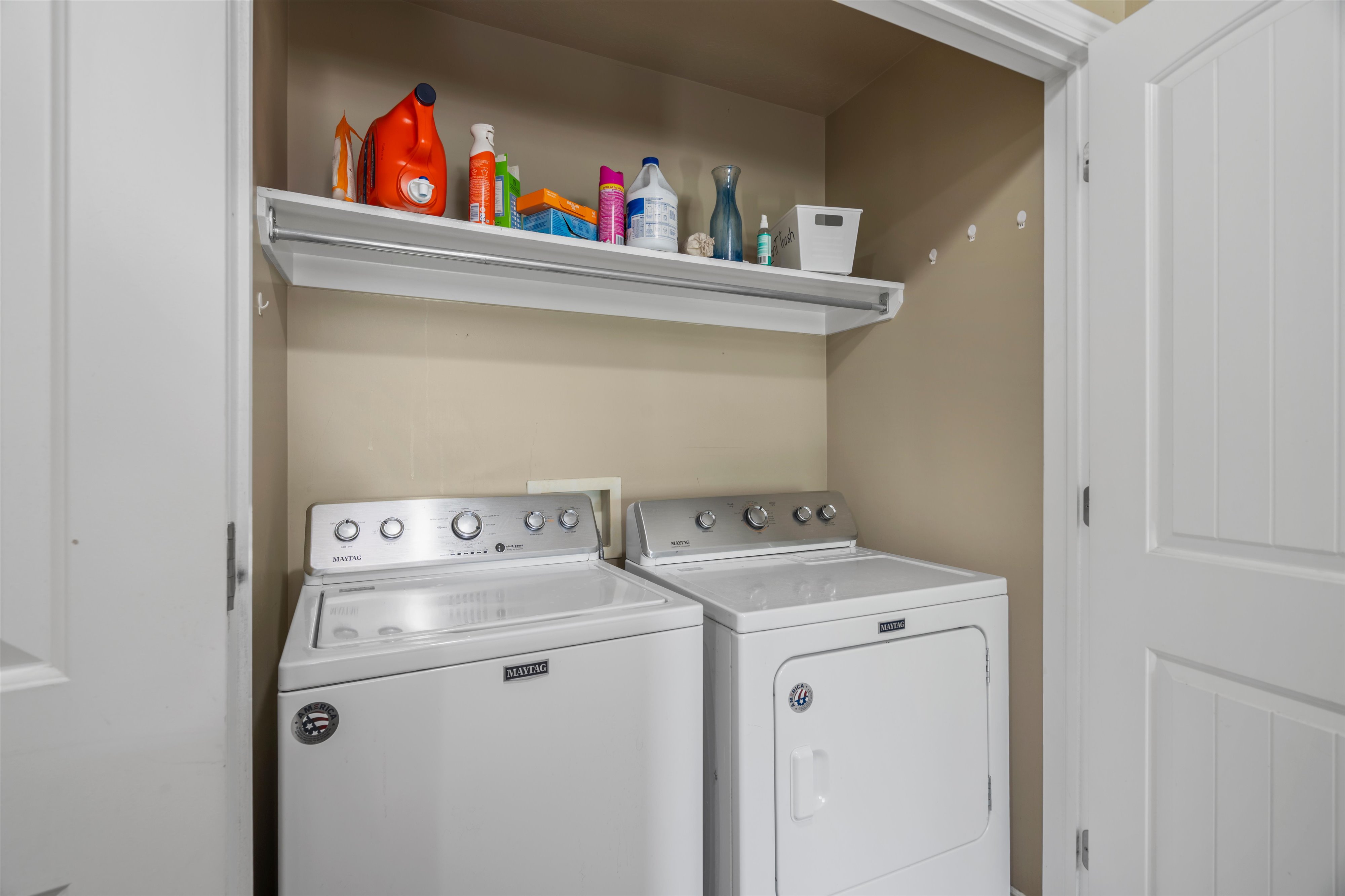 Dedicated laundry area featuring a white shelving unit, hanging rod, and light beige wall paint