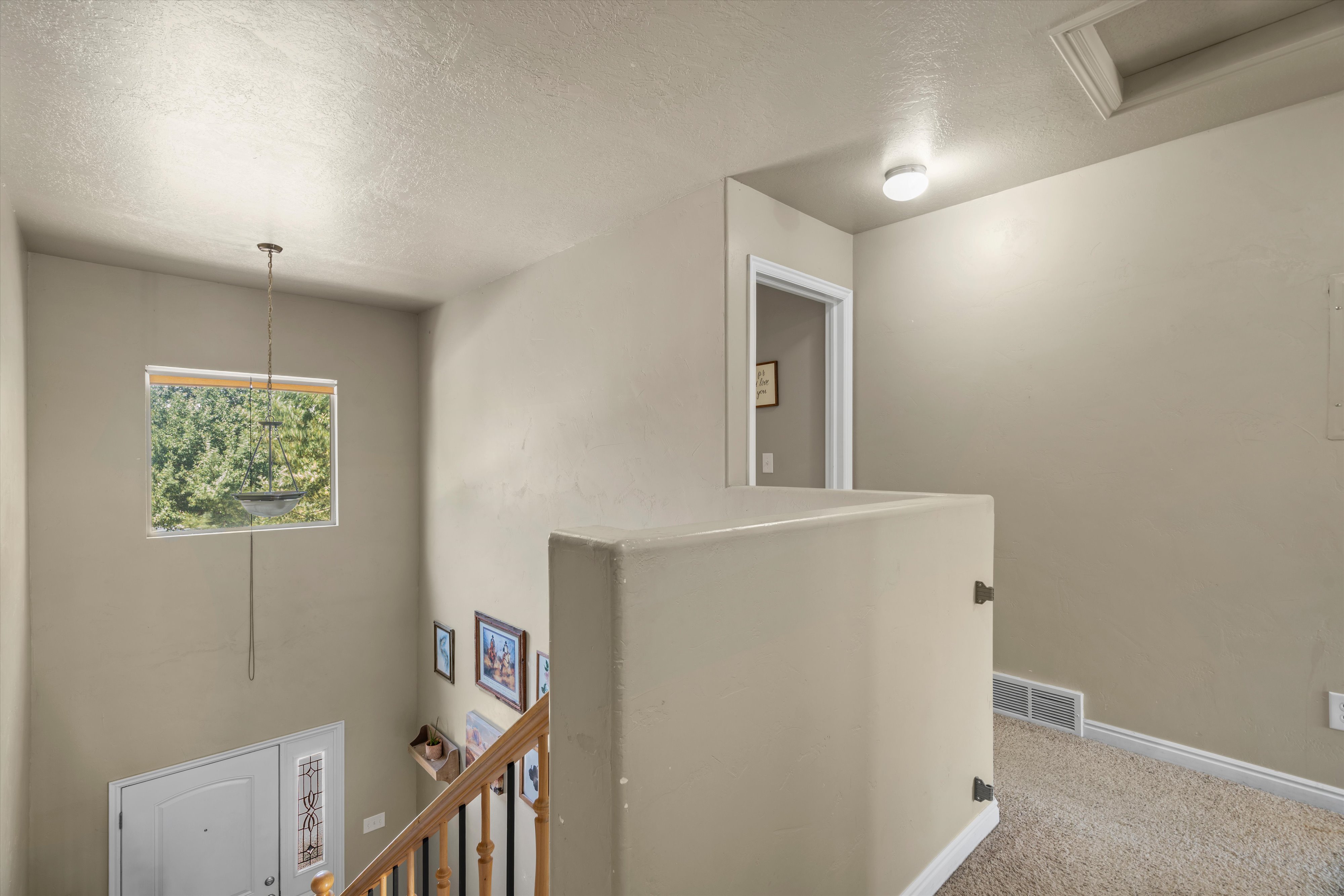 Two-story entryway featuring a decorative light fixture and a window with natural light