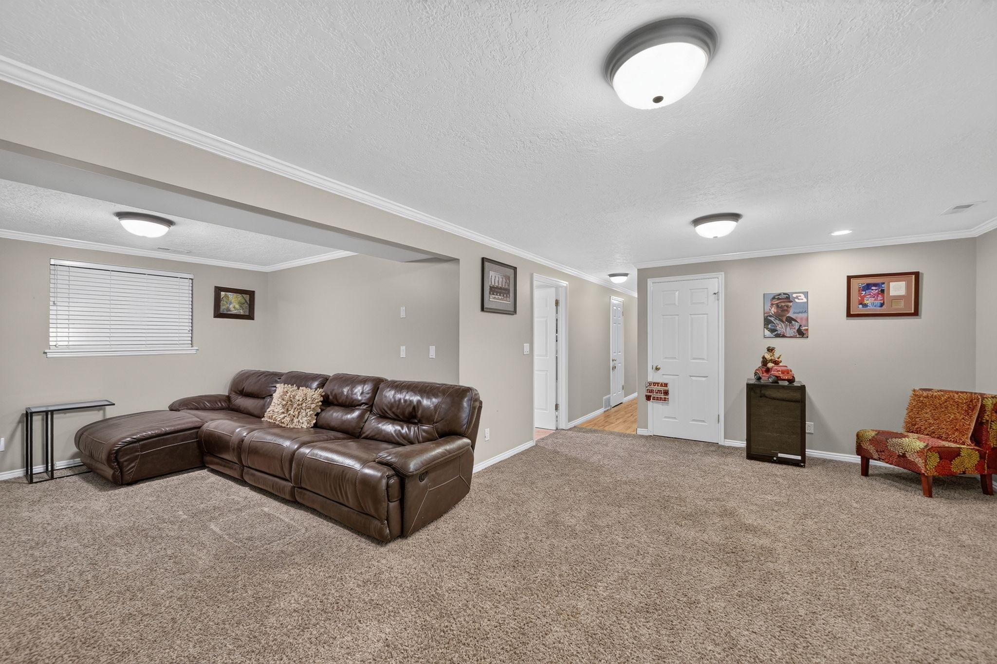 Spacious living area featuring neutral-toned walls, crown molding, and plush carpet flooring
