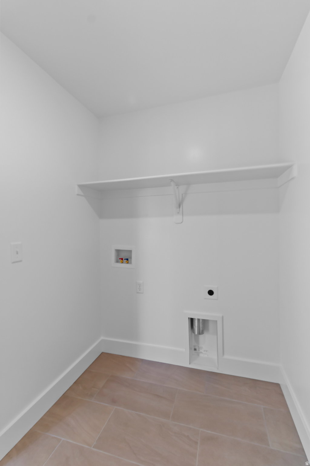 Laundry area featuring tile flooring, white baseboards, and a built-in wall shelf