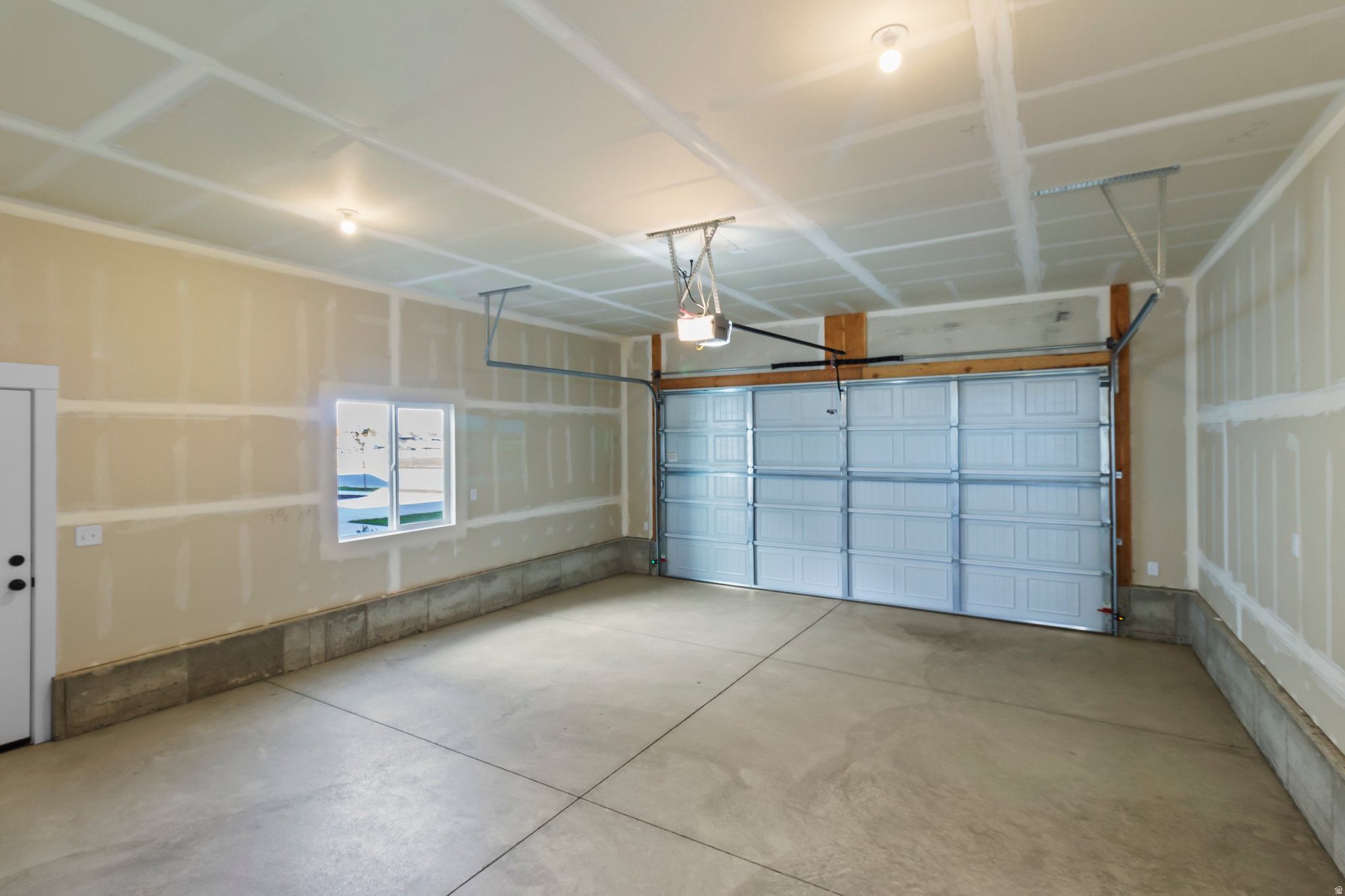 Spacious garage featuring a concrete floor, overhead lighting, and a single window